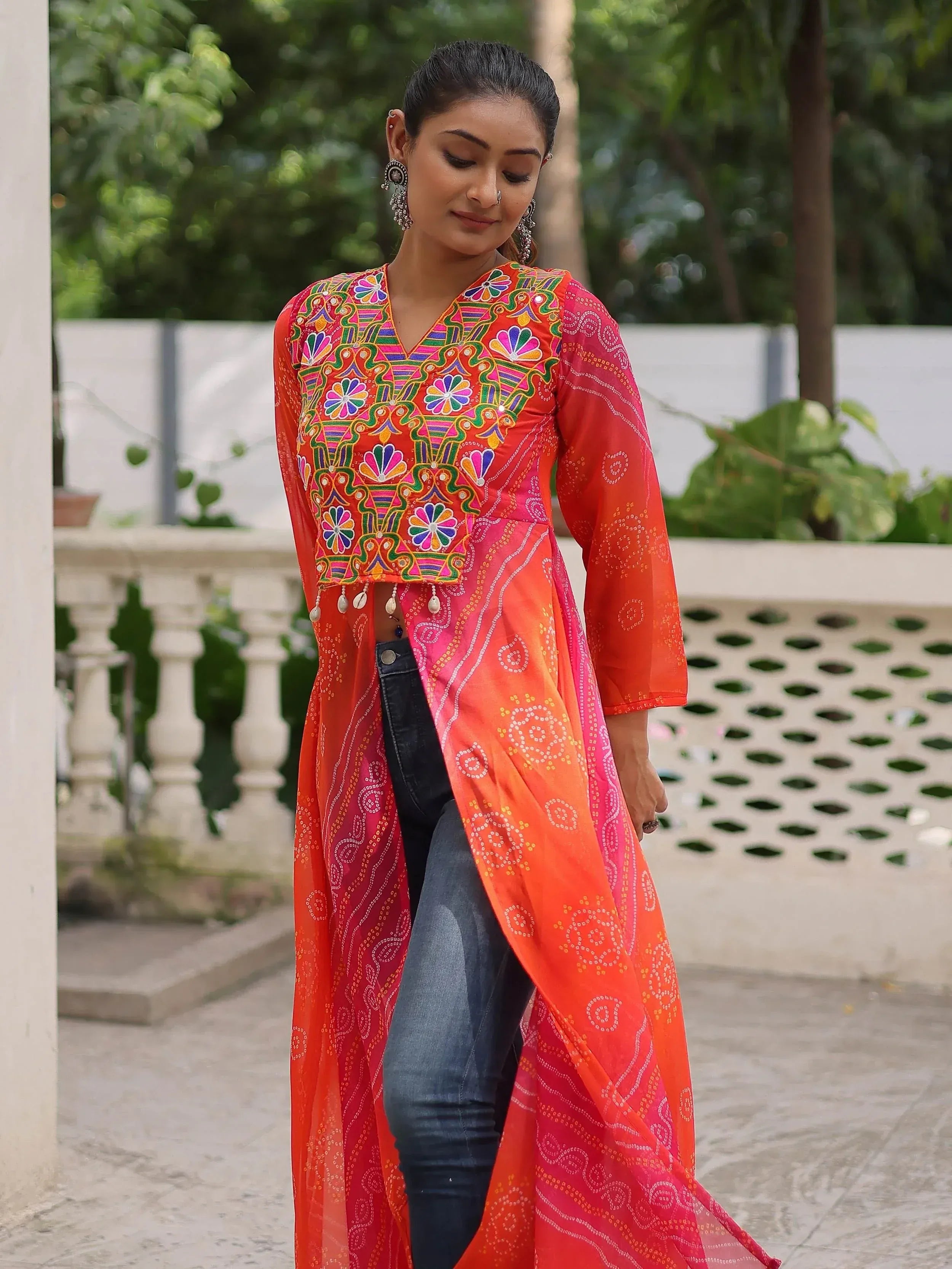Vibrant orange and pink embroidered ethnic kurti with floral motifs, paired with jeans for a fusion look.