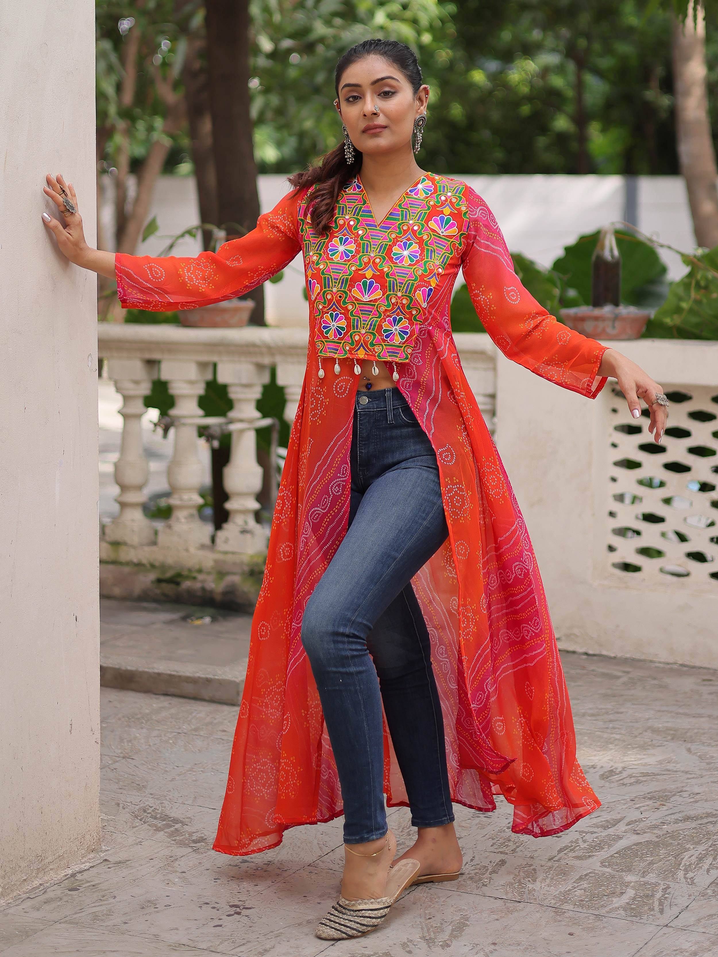 Vibrant orange embroidered ethnic kurta with mirror work, paired with jeans for a fusion look