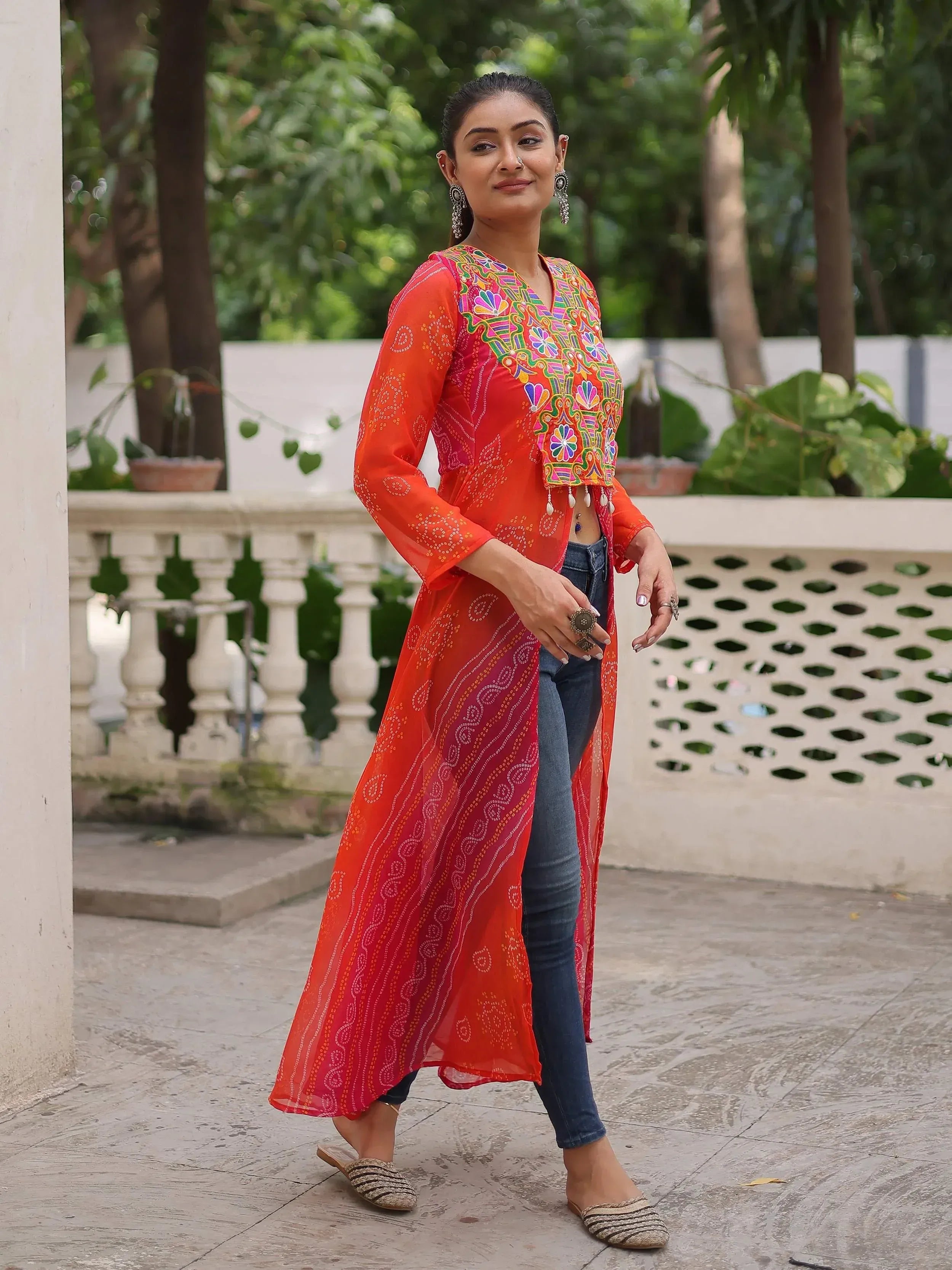 Vibrant orange embroidered ethnic kurta with mirror work, paired with jeans and juttis for a fusion look