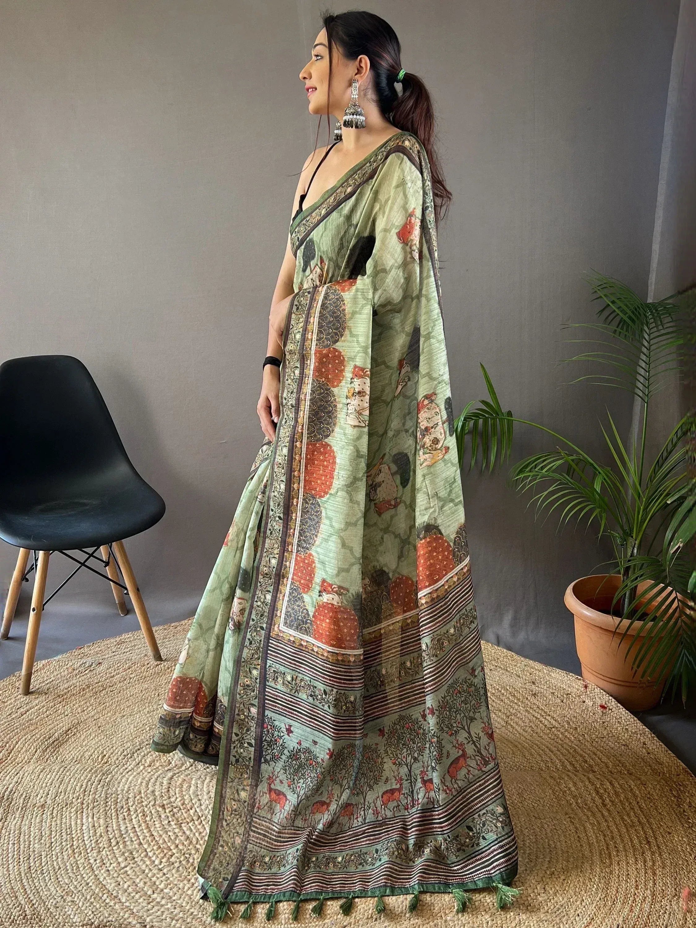 Woman in green printed saree with deer and floral motifs, ethnic Indian wear