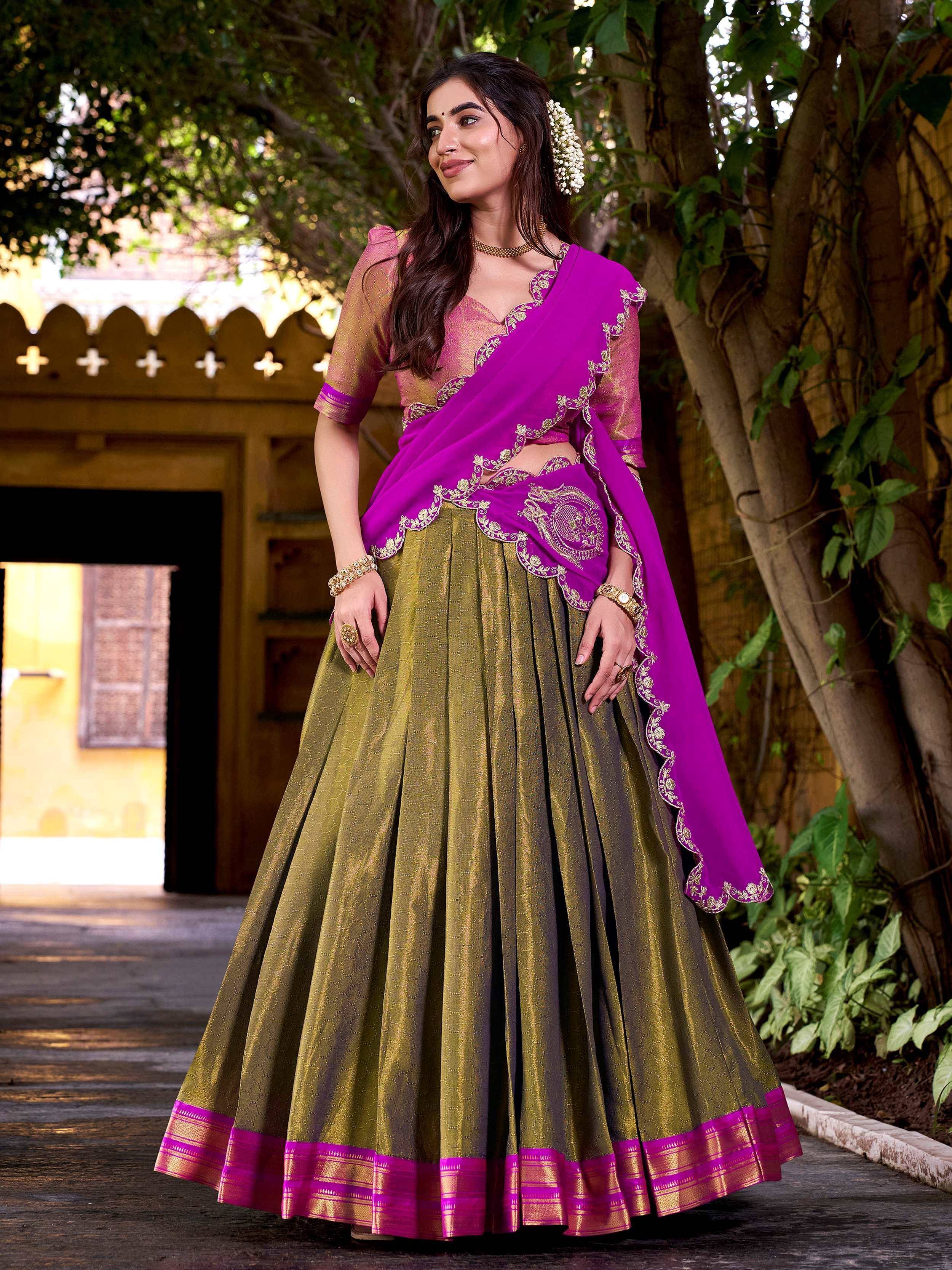 Woman in vibrant purple and gold lehenga choli with intricate embroidery, perfect for Indian ethnic wear occasions.