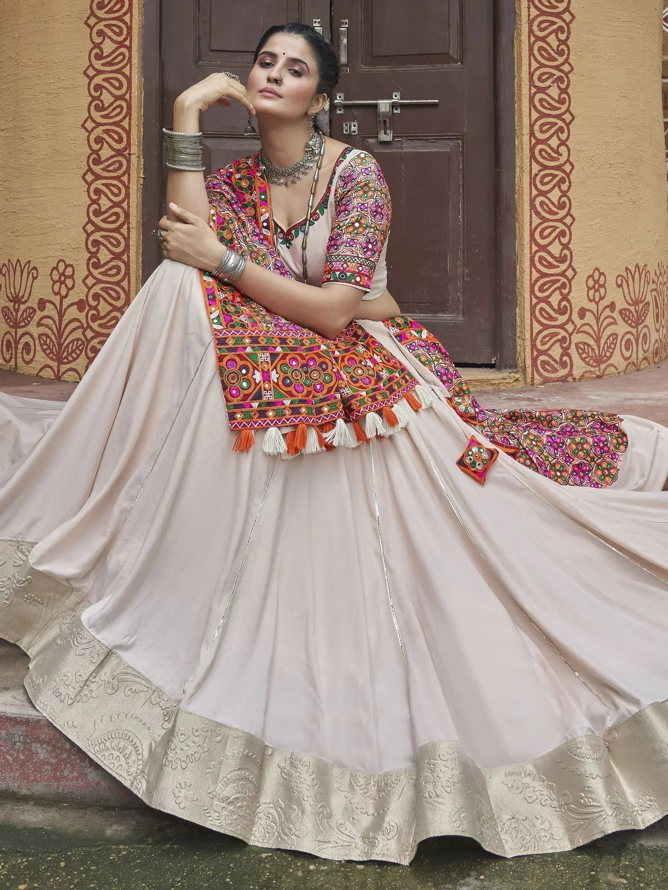 Woman in embroidered Indian lehenga choli with colorful mirror work and tassels, traditional ethnic wear
