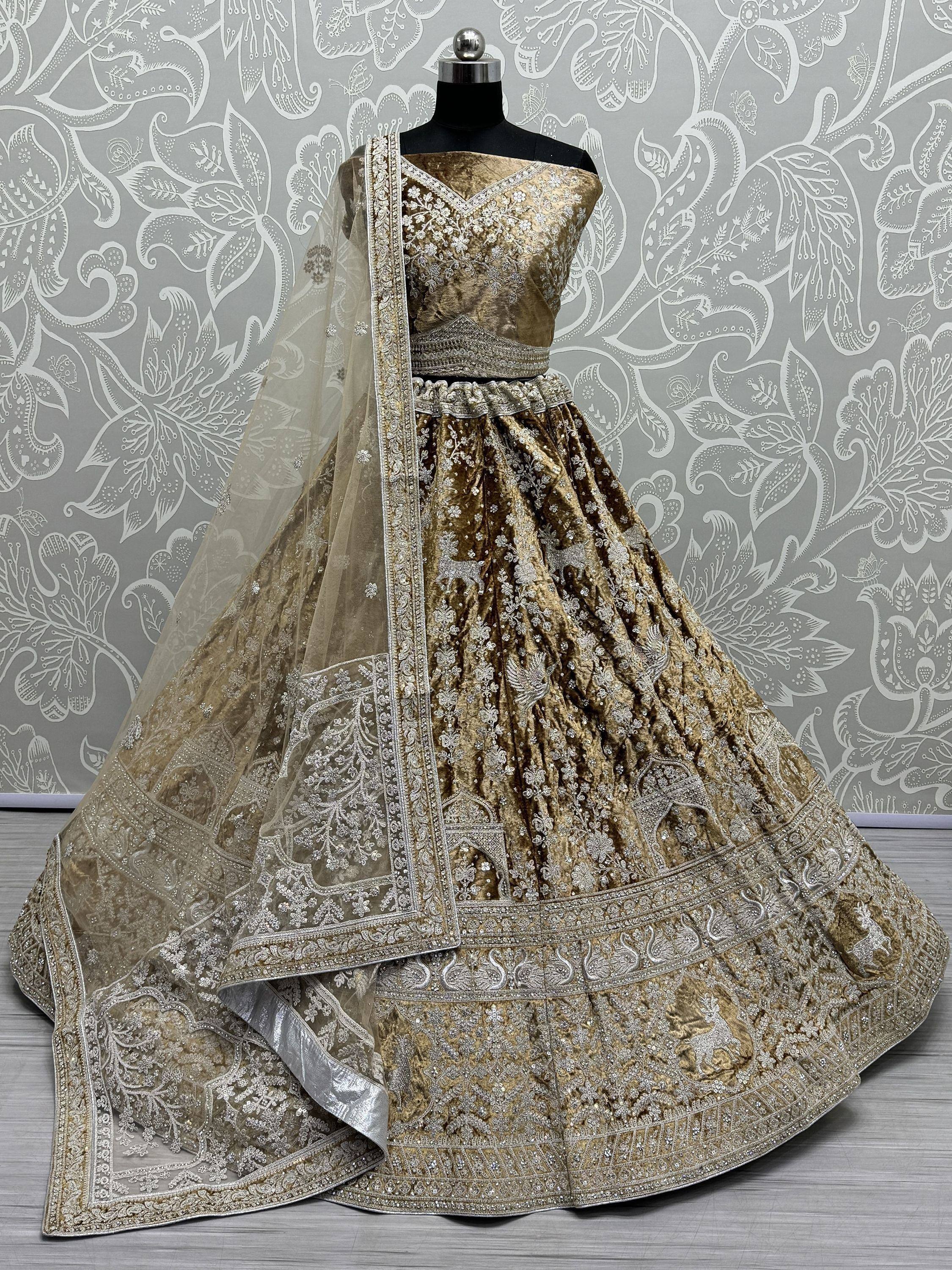 Golden velvet designer lehenga choli with intricate silver embroidery and sheer dupatta, perfect for Indian weddings.