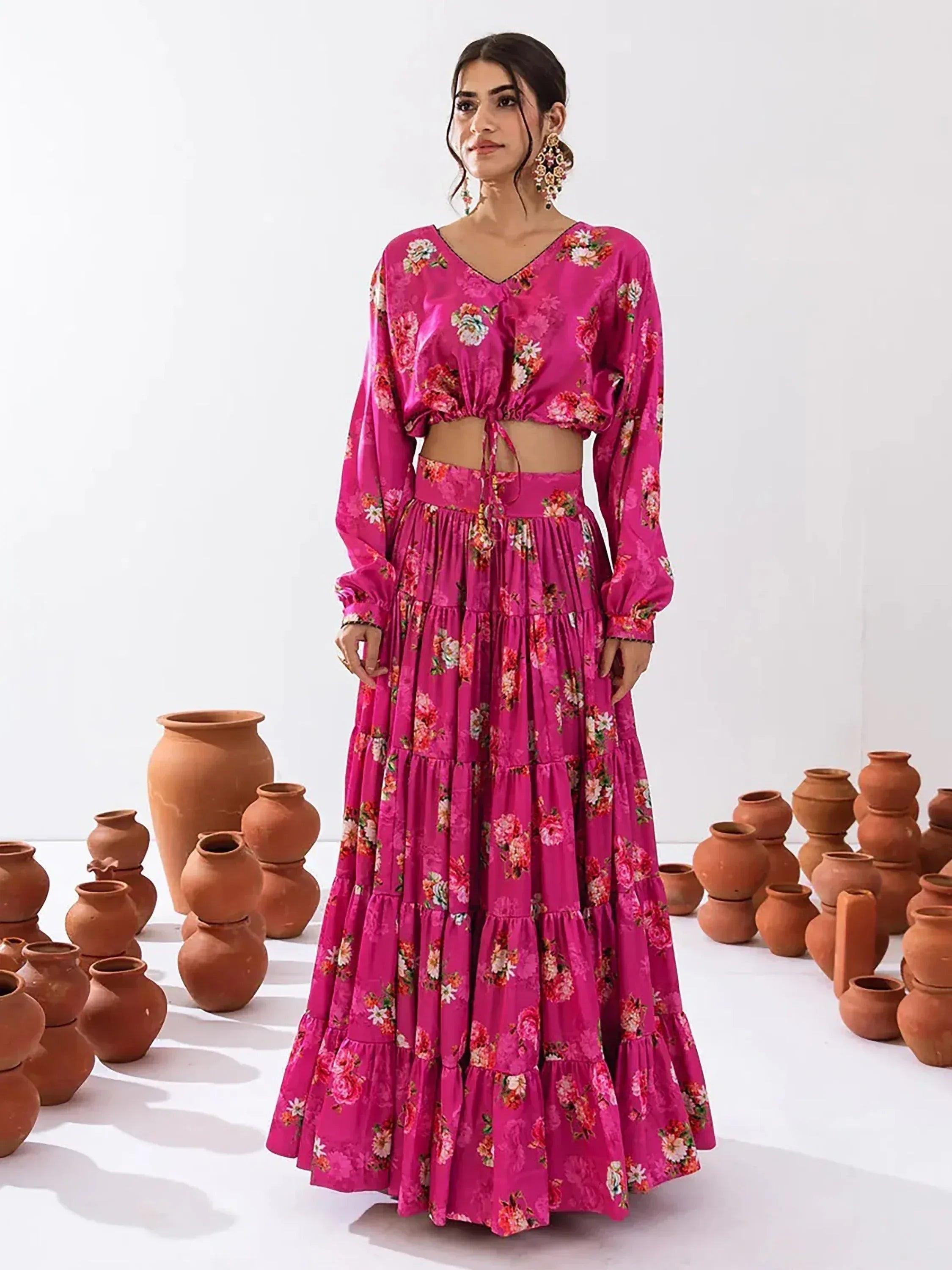 Pink floral ethnic lehenga choli with tiered skirt and long sleeves, styled with clay pots