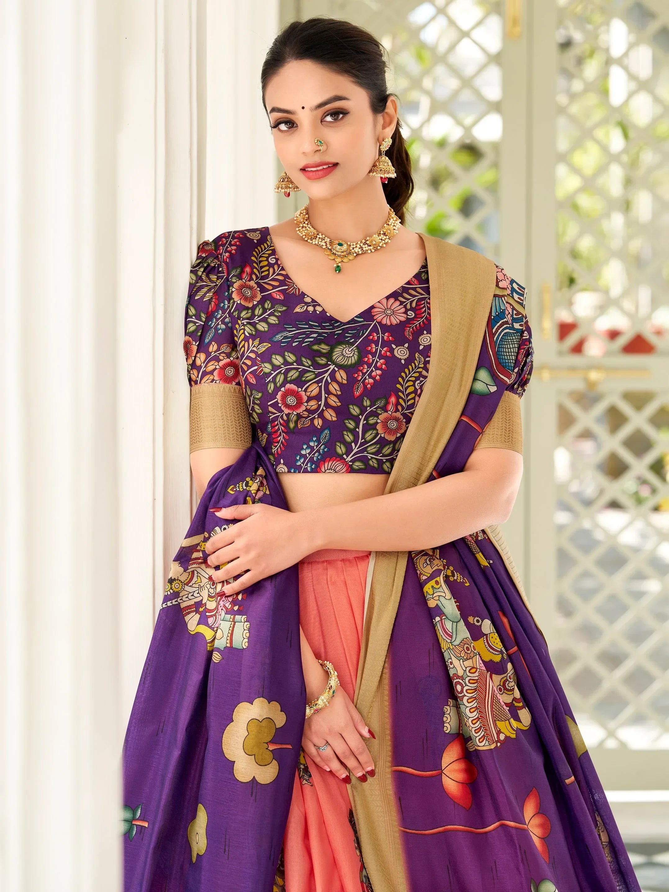 Purple floral print lehenga choli with gold trim, paired with coral skirt and traditional jewelry for Indian ethnic wear