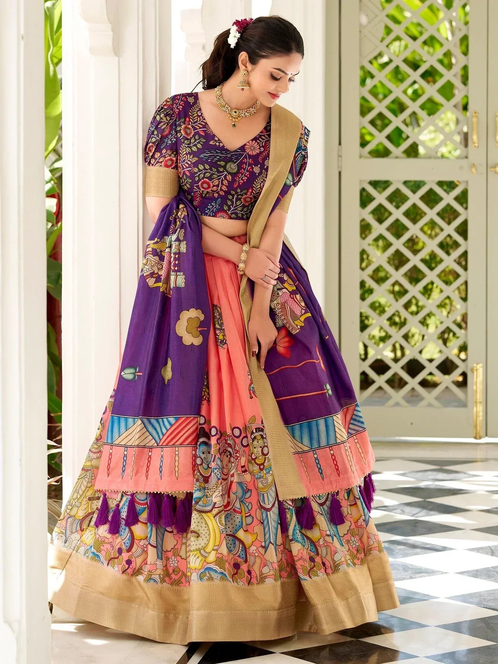 Woman in vibrant purple and pink printed lehenga choli with gold border, perfect for Indian ethnic wear occasions