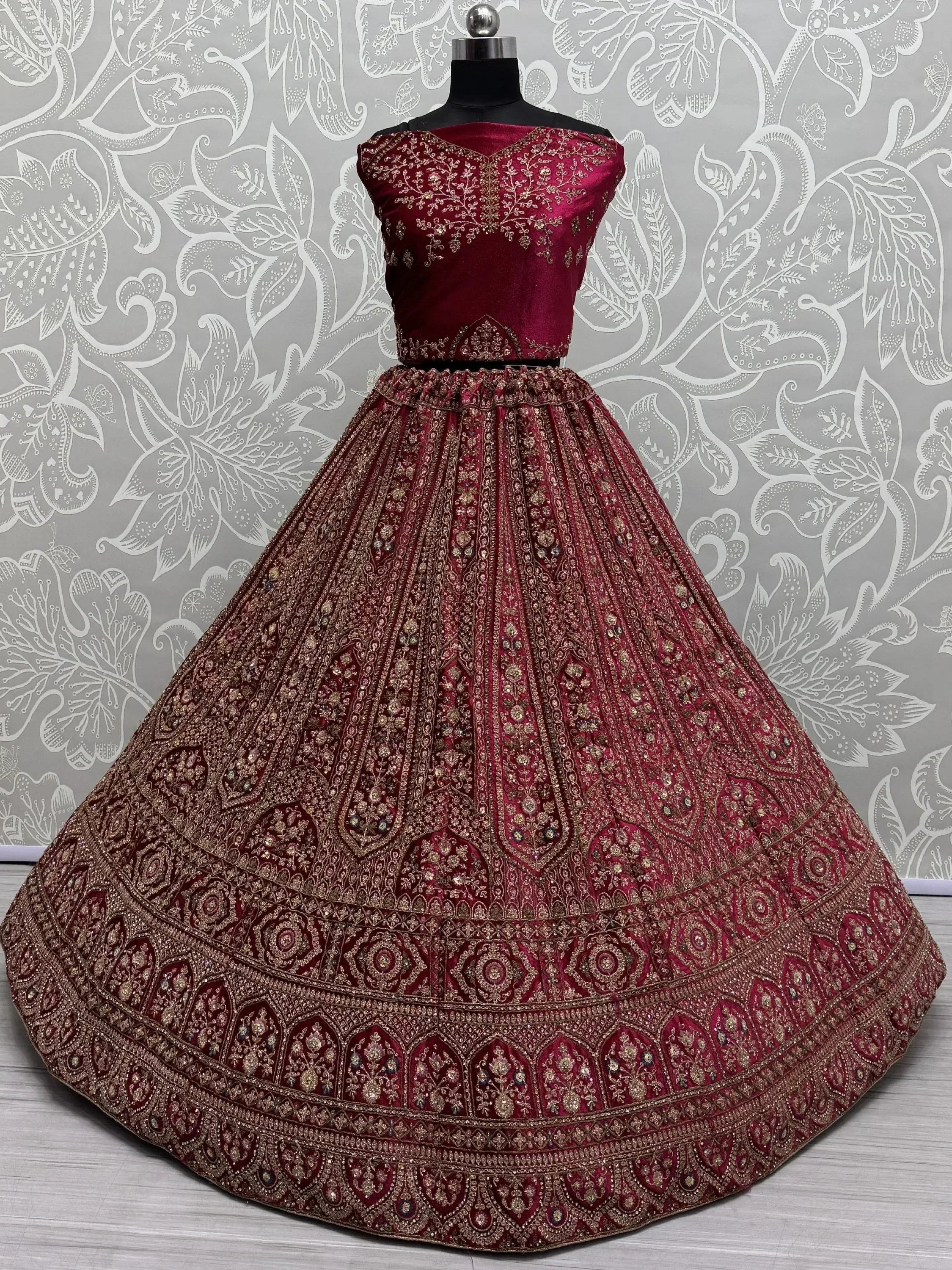 Burgundy velvet lehenga choli with heavy gold embroidery, perfect for Indian weddings and festive occasions.