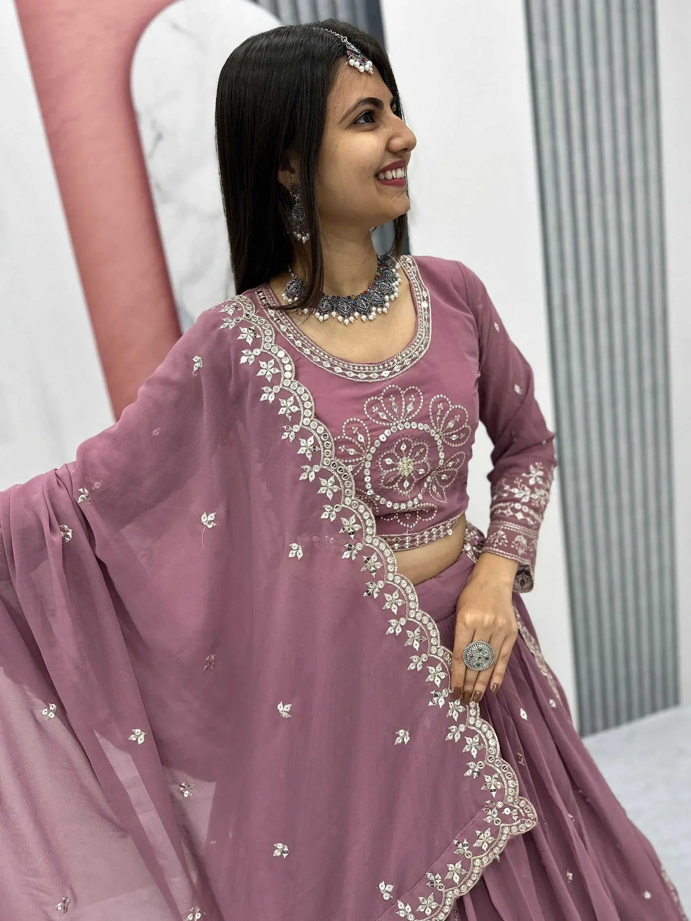 Woman in dusty rose Indian lehenga choli with silver embroidery and traditional jewelry