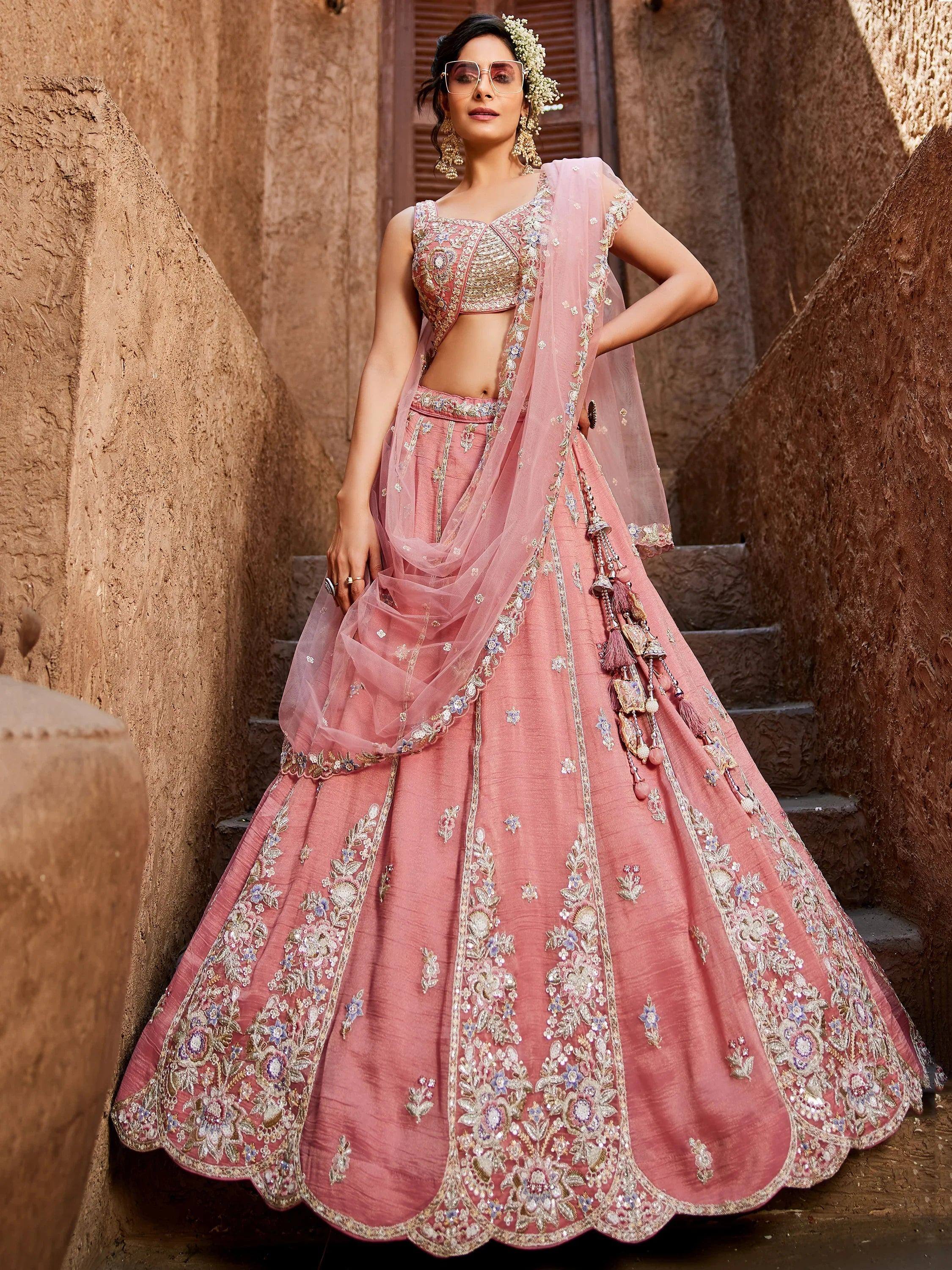 Pink embroidered lehenga choli with floral motifs and tassels, perfect for Indian weddings and festive occasions.