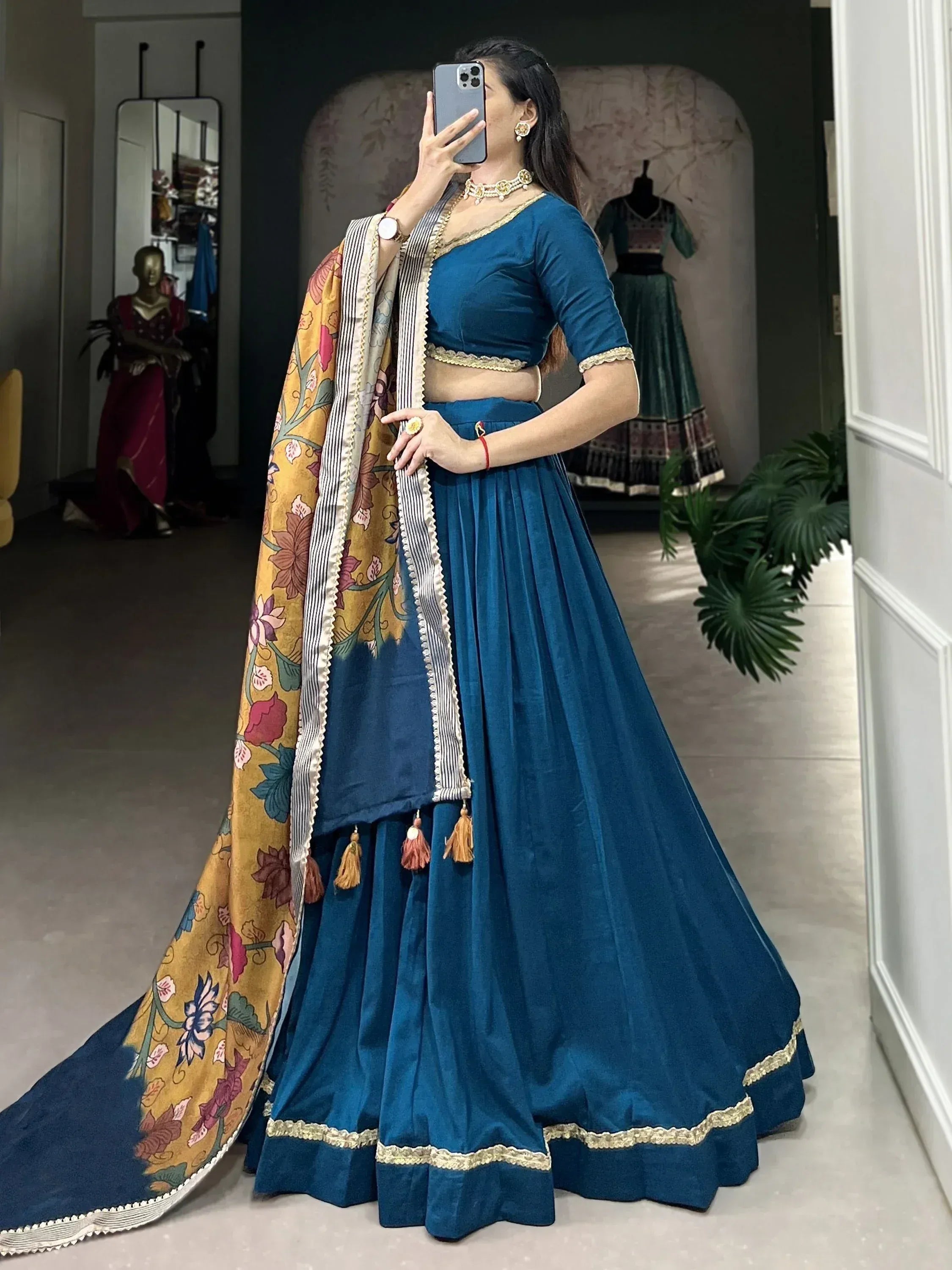 Teal velvet lehenga choli with floral dupatta, gold trim, and tassels for Indian ethnic wear