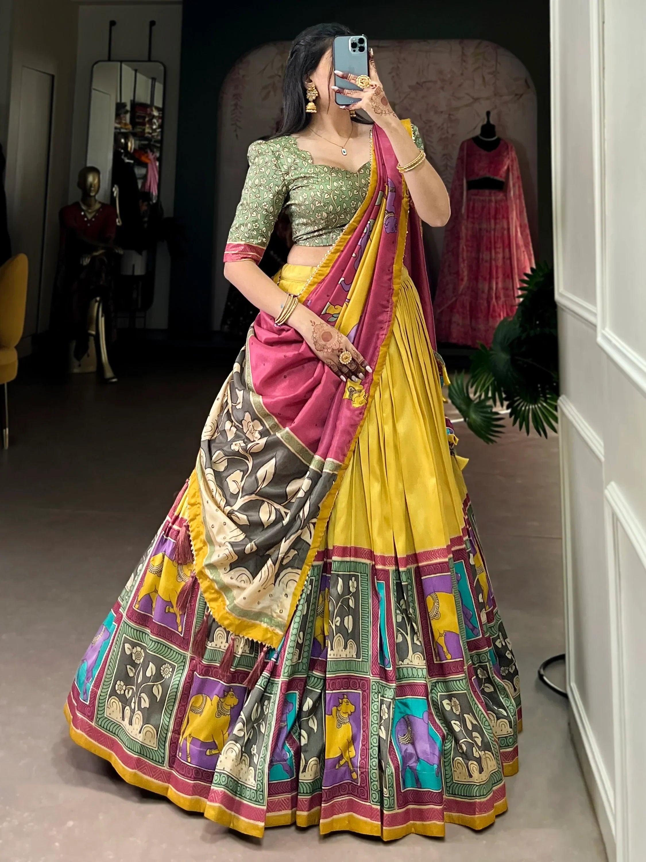 Woman in vibrant yellow and pink printed lehenga choli with floral and elephant motifs, perfect for Indian ethnic wear.