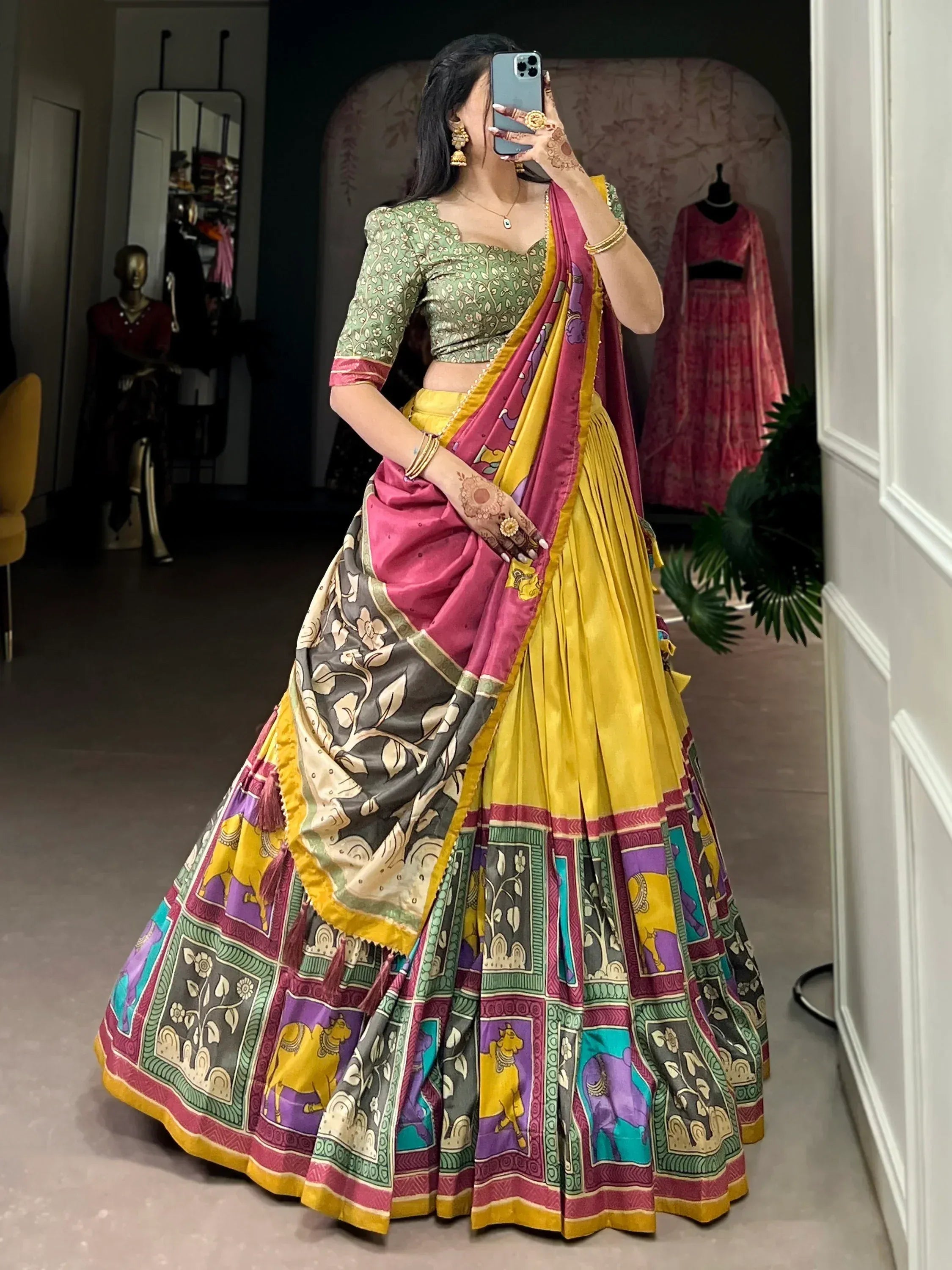 Woman in vibrant yellow and pink printed lehenga choli with floral and elephant motifs, perfect for Indian ethnic wear.
