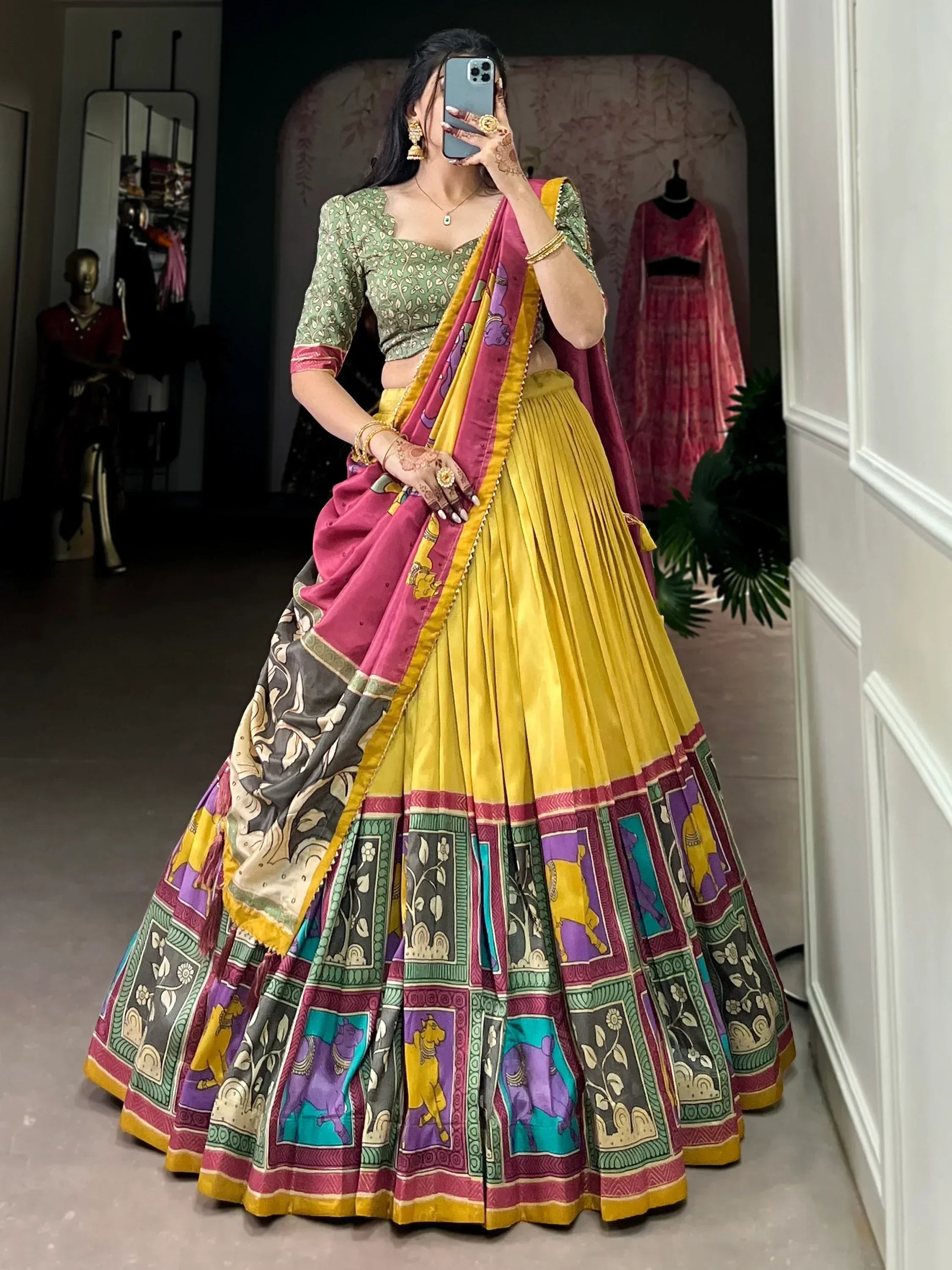 Woman in vibrant yellow and pink printed lehenga choli with floral blouse, perfect for Indian ethnic wear occasions.