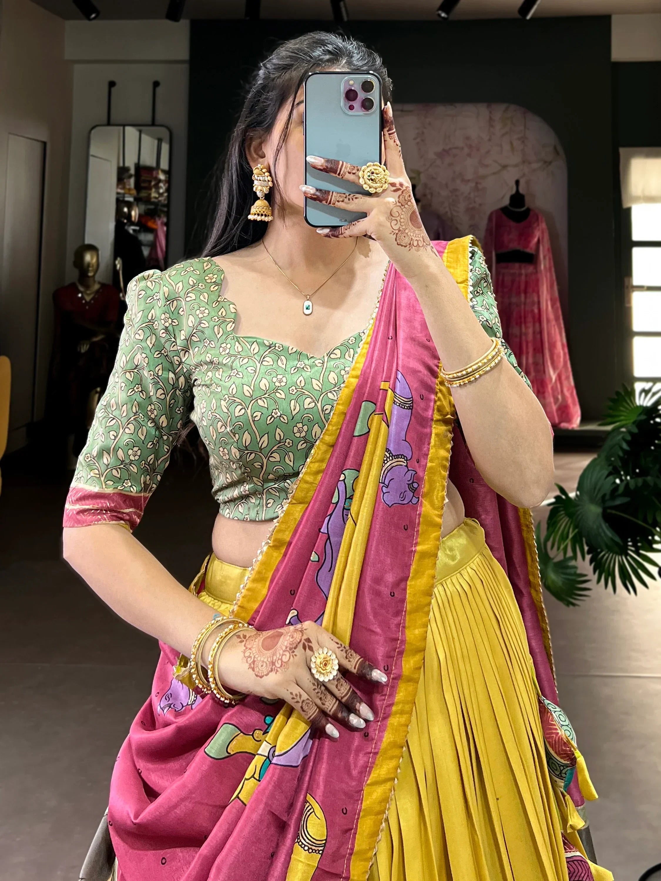 Woman in vibrant Indian lehenga choli with floral blouse, pink and yellow dupatta, and traditional jewelry