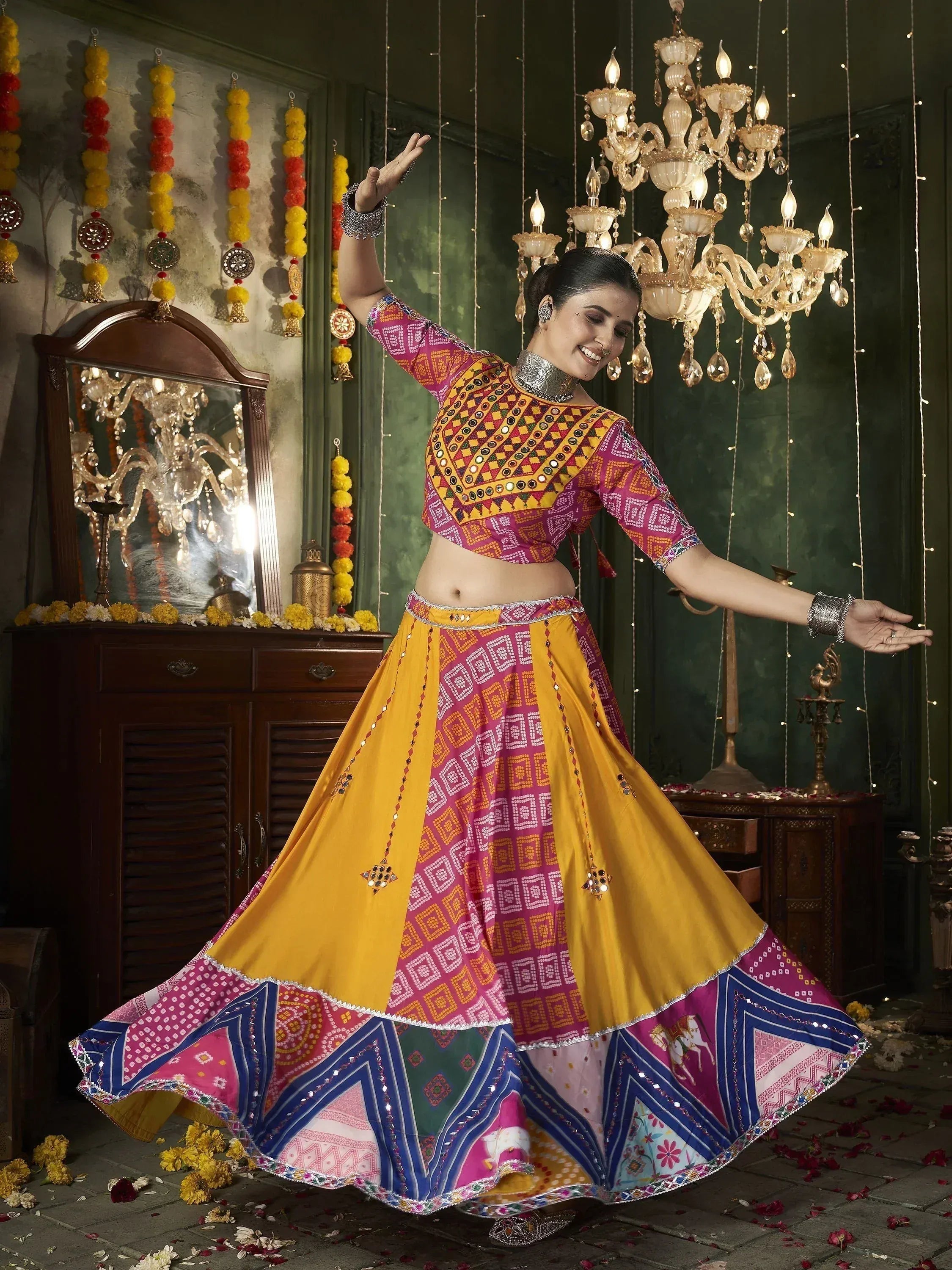 Woman dancing in vibrant yellow and pink ethnic lehenga choli with mirror work, festive decor