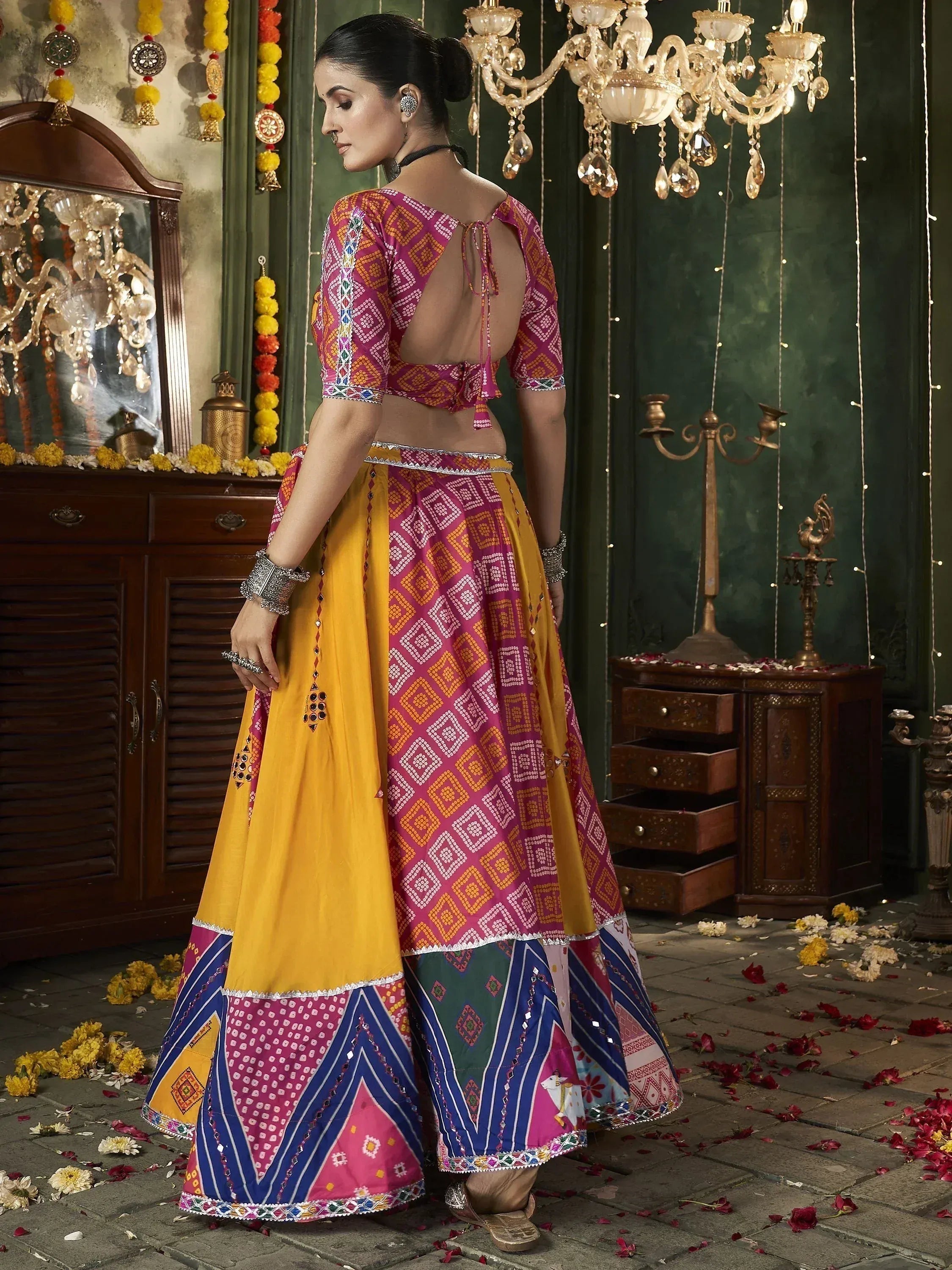 Woman in vibrant pink and yellow ethnic lehenga choli with geometric print, backless blouse, festive decor