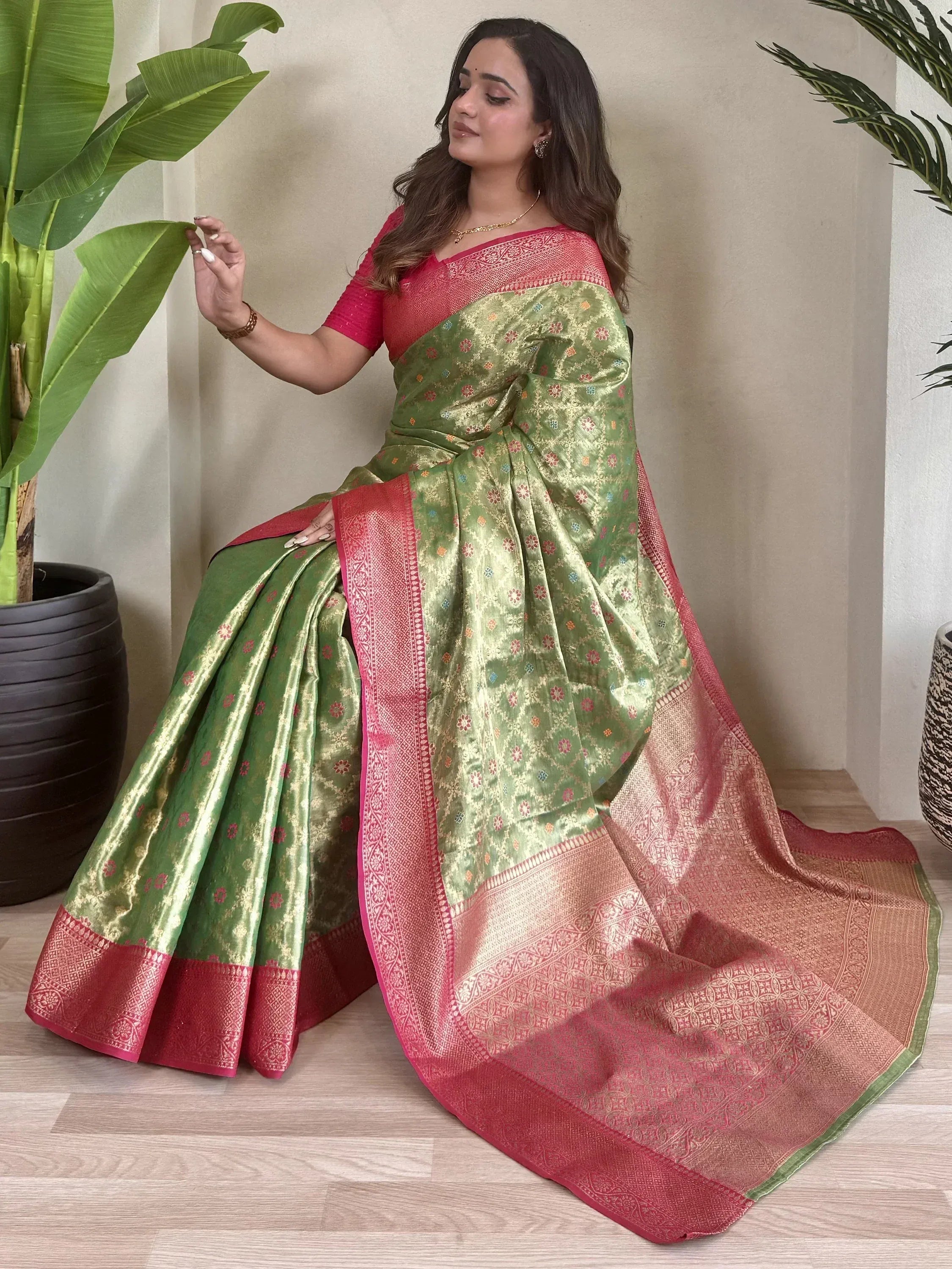 Green and pink designer saree with floral motifs and woven border, styled with matching blouse for ethnic wear
