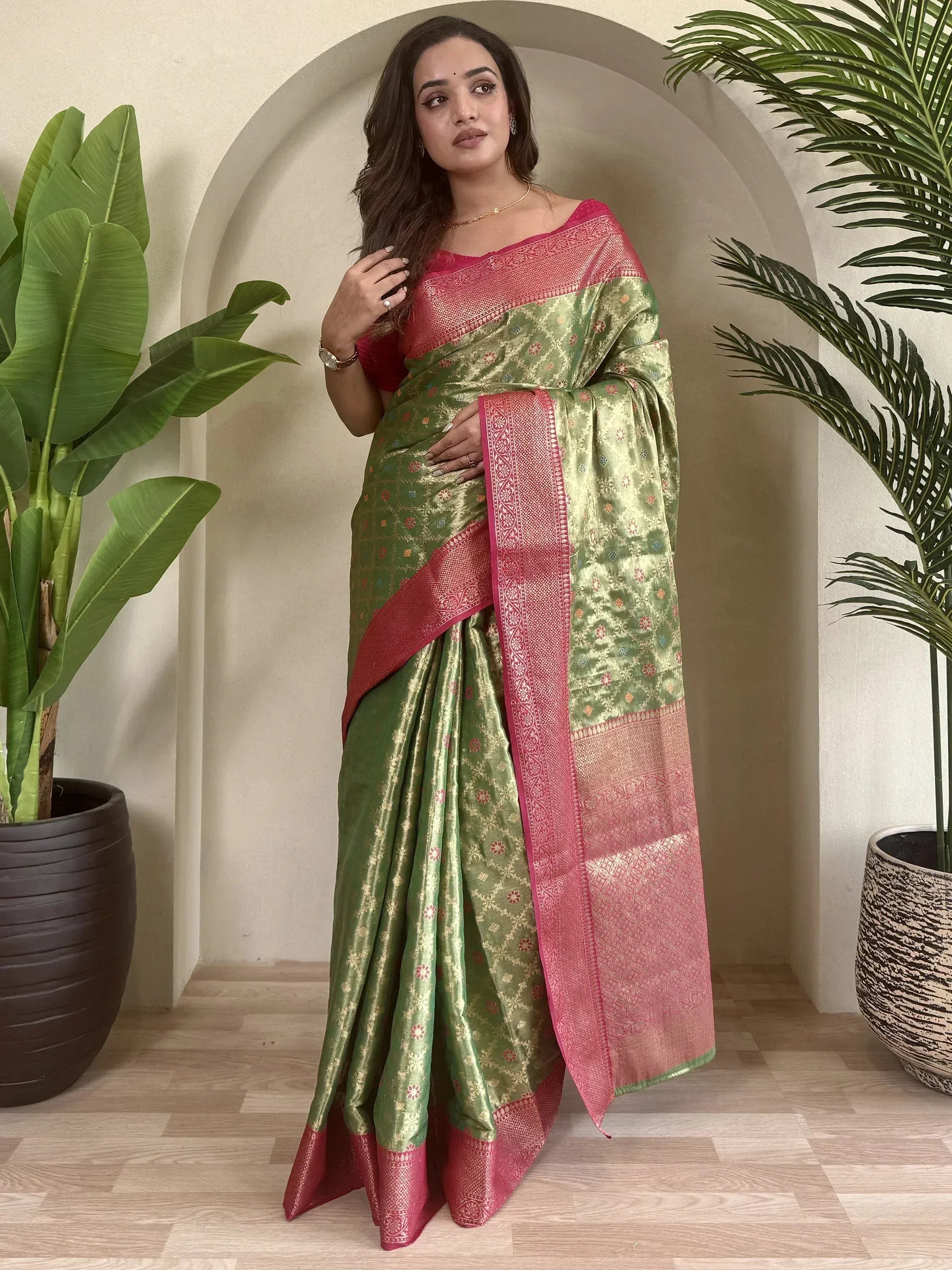 Green and pink designer saree with gold floral motifs and intricate border, styled for ethnic wear