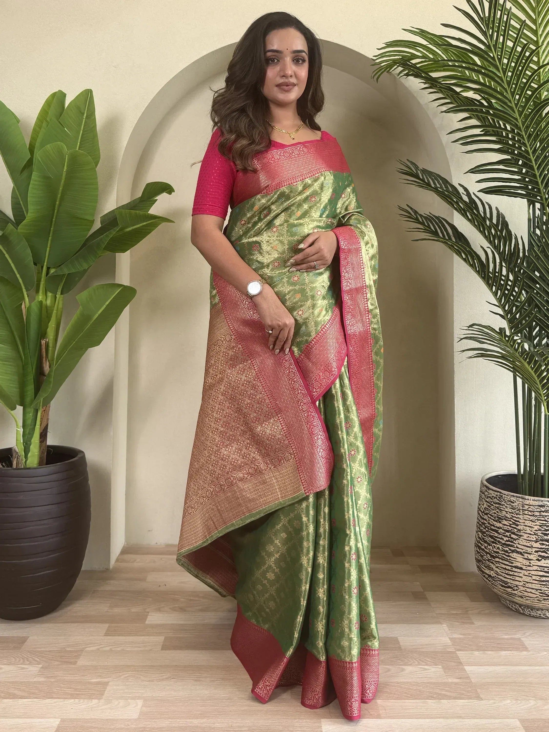 Green and pink designer saree with gold floral motifs and woven border, paired with matching blouse