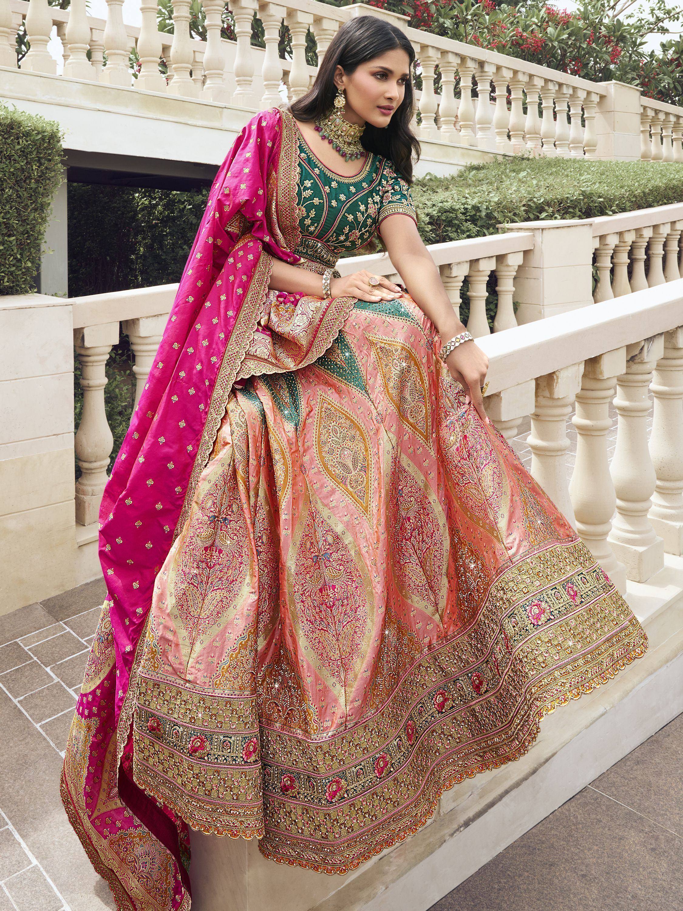 Woman in designer lehenga choli with pink dupatta, floral embroidery, and gold detailing for Indian ethnic wear.