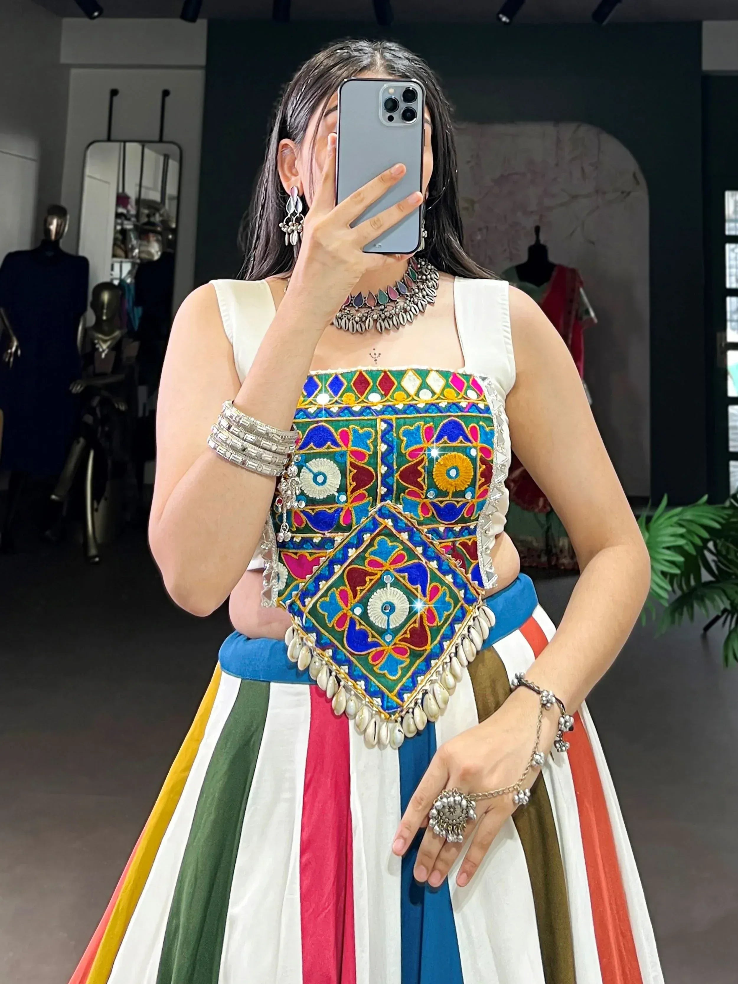 Woman in colorful embroidered ethnic top and striped skirt, mirror selfie with traditional jewelry