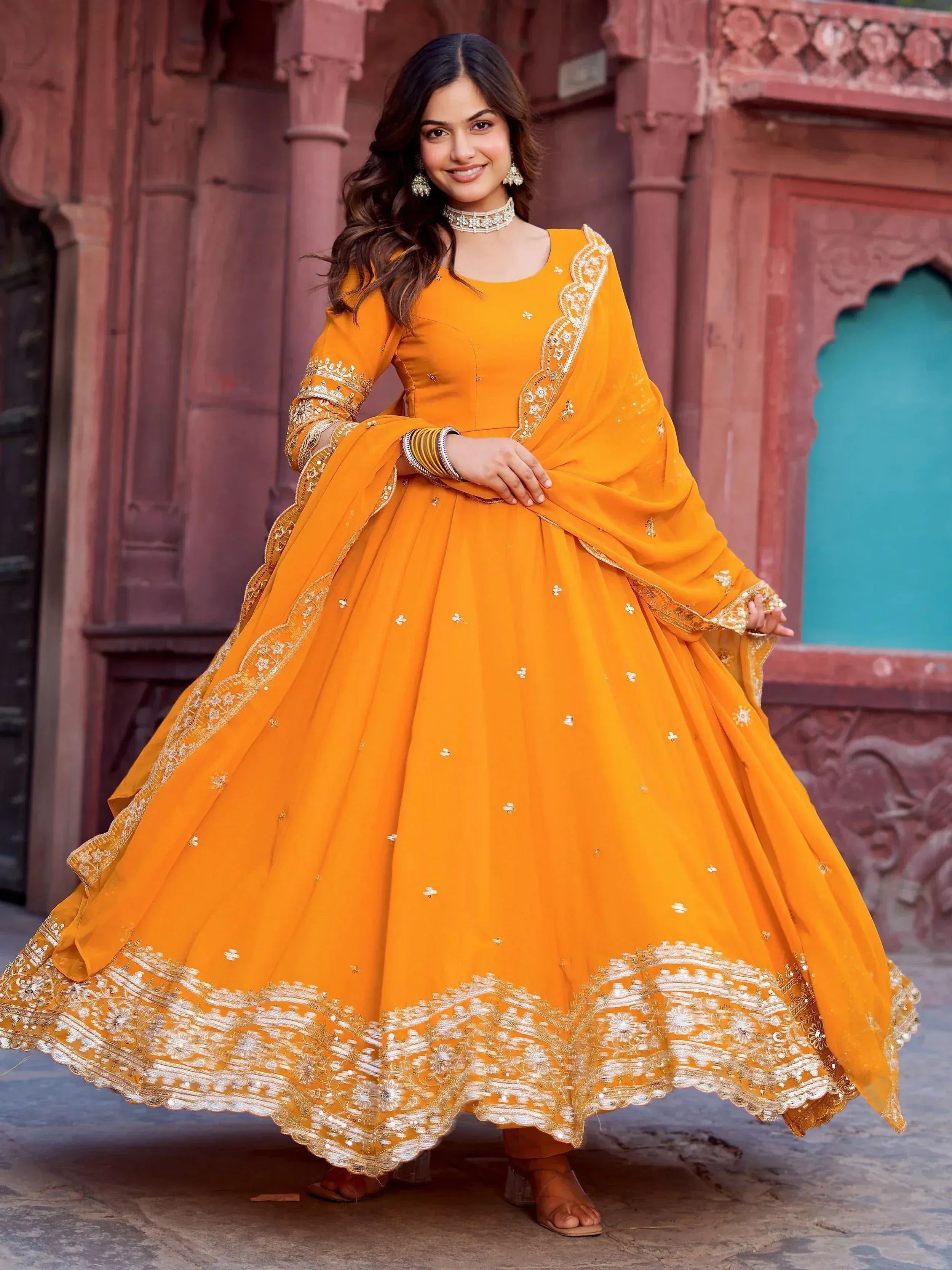 Vibrant orange Indian anarkali suit with gold embroidery, perfect for festive occasions and weddings.