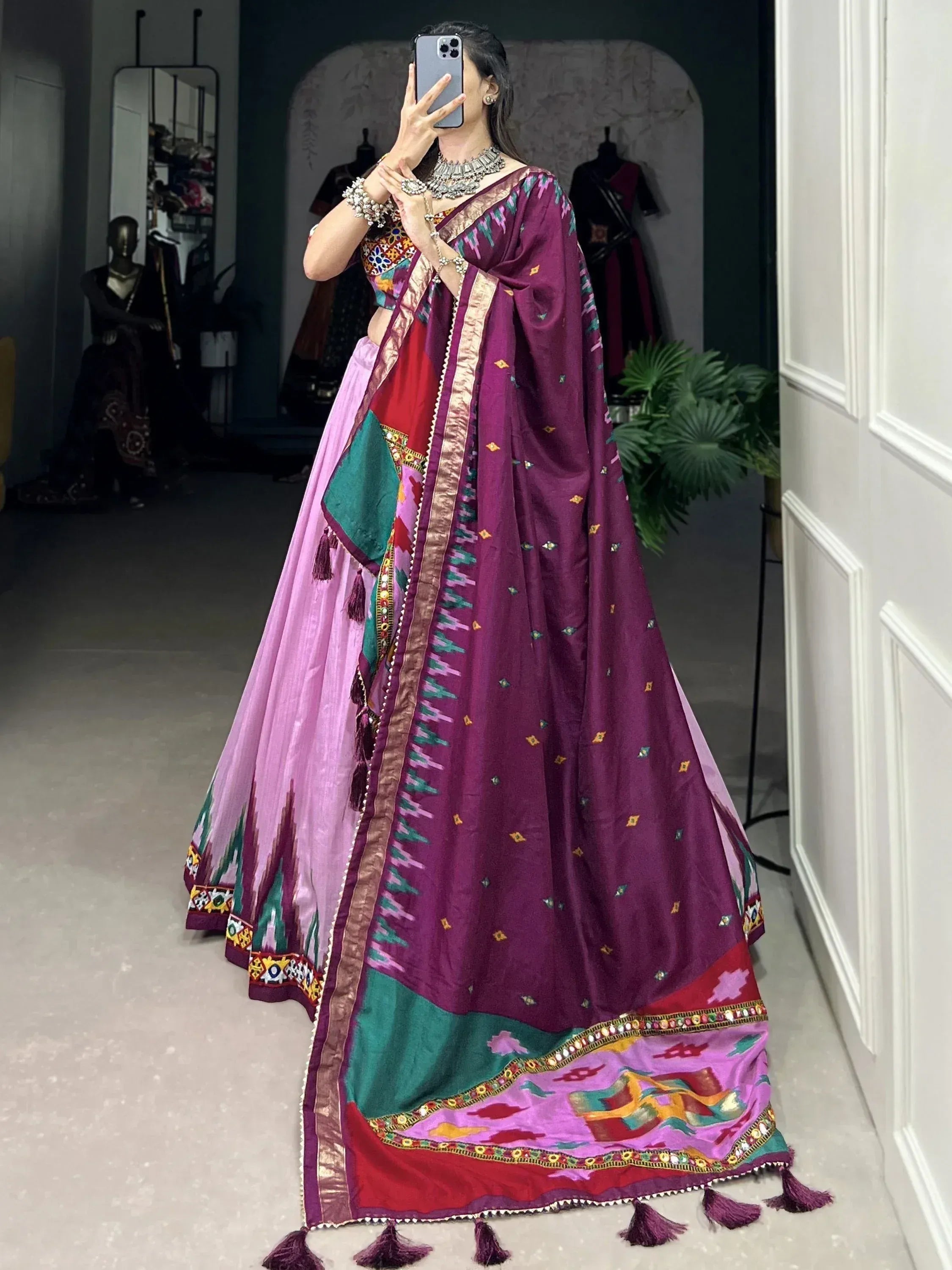 Vibrant purple and pink ethnic lehenga choli with intricate embroidery and tassels, perfect for festive occasions.