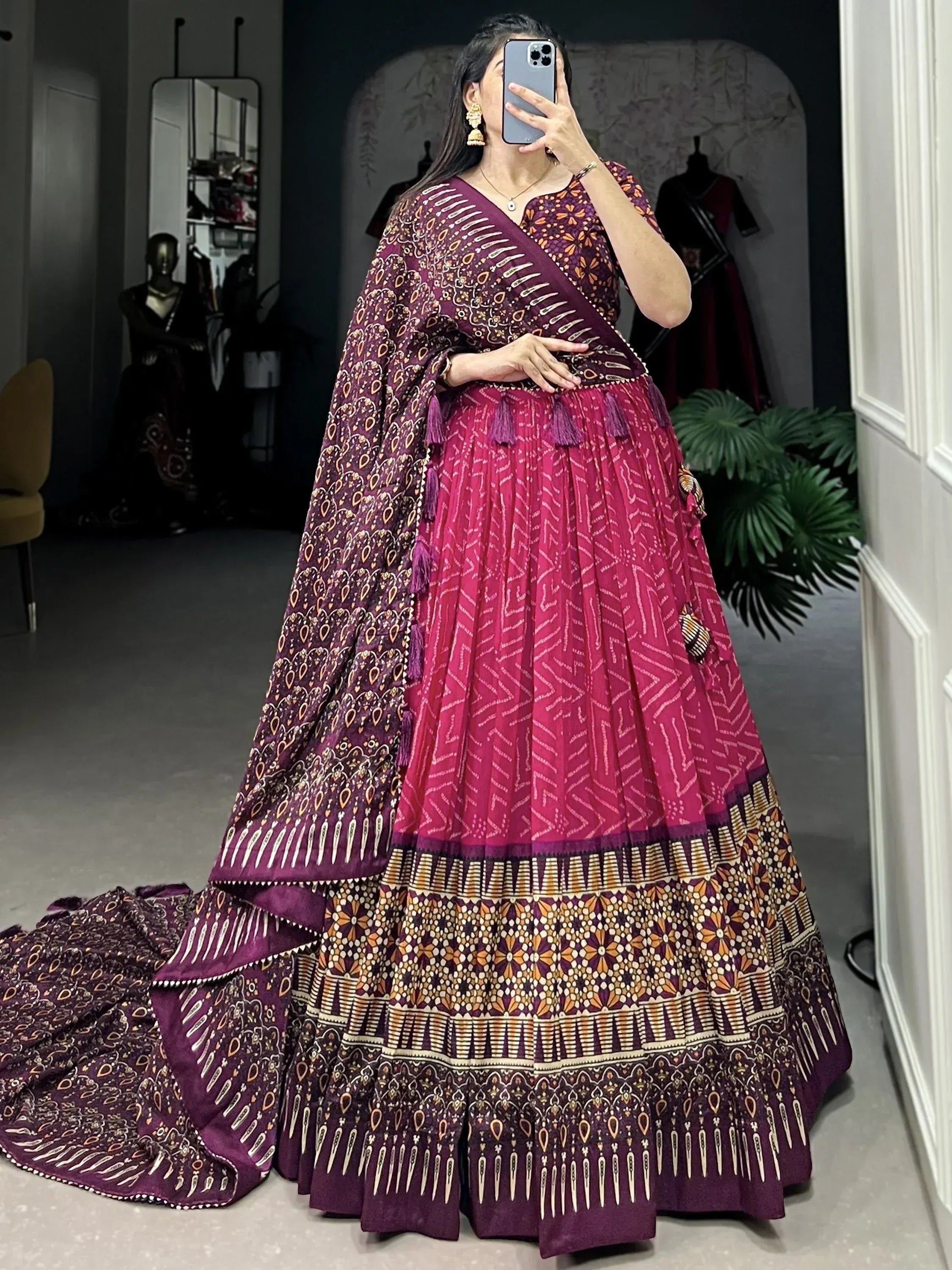 Woman wearing purple and pink printed lehenga choli with tassels, perfect for Indian ethnic occasions