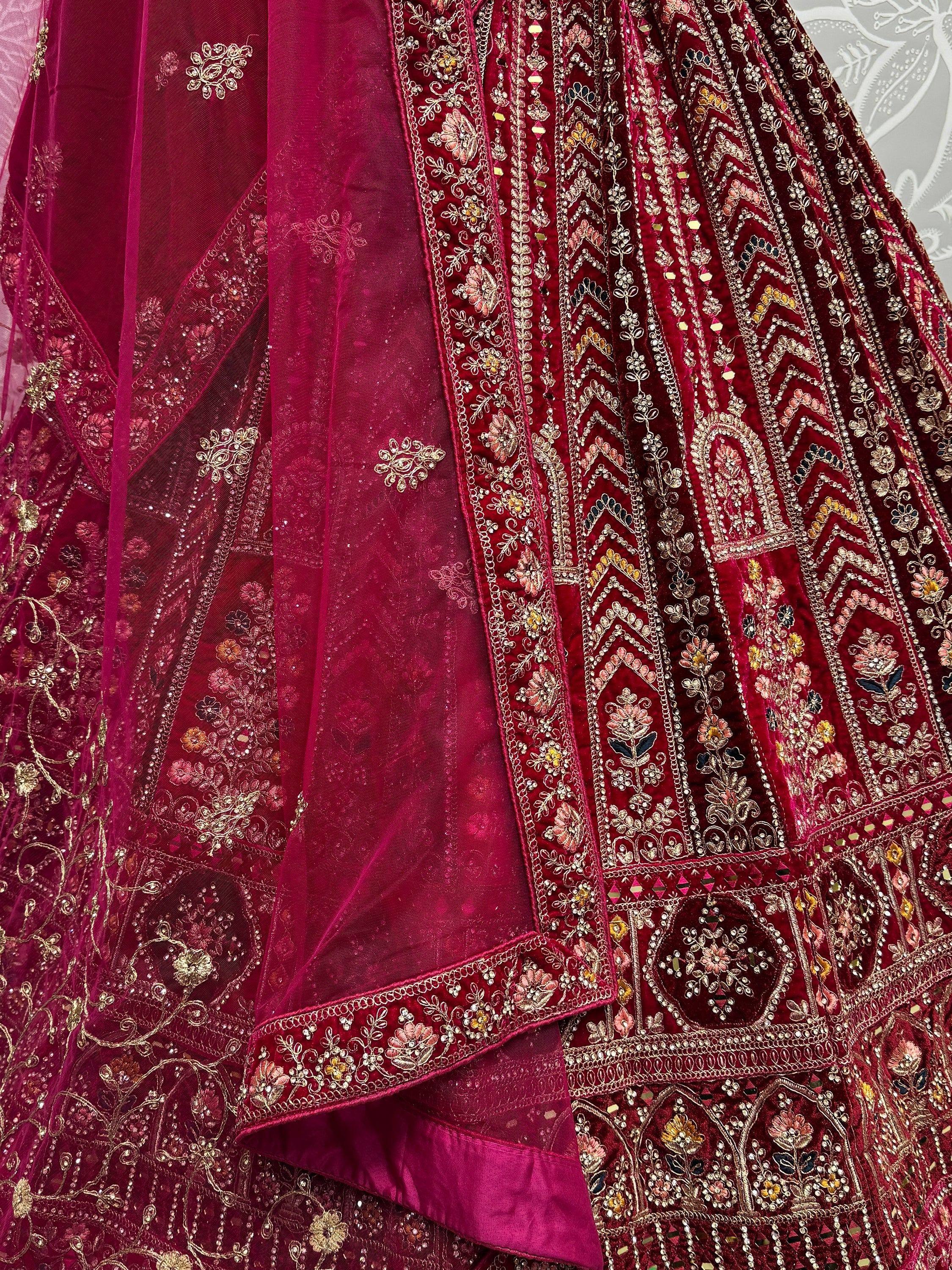 Luxury maroon velvet lehenga choli with intricate gold embroidery and floral motifs, perfect for Indian weddings.