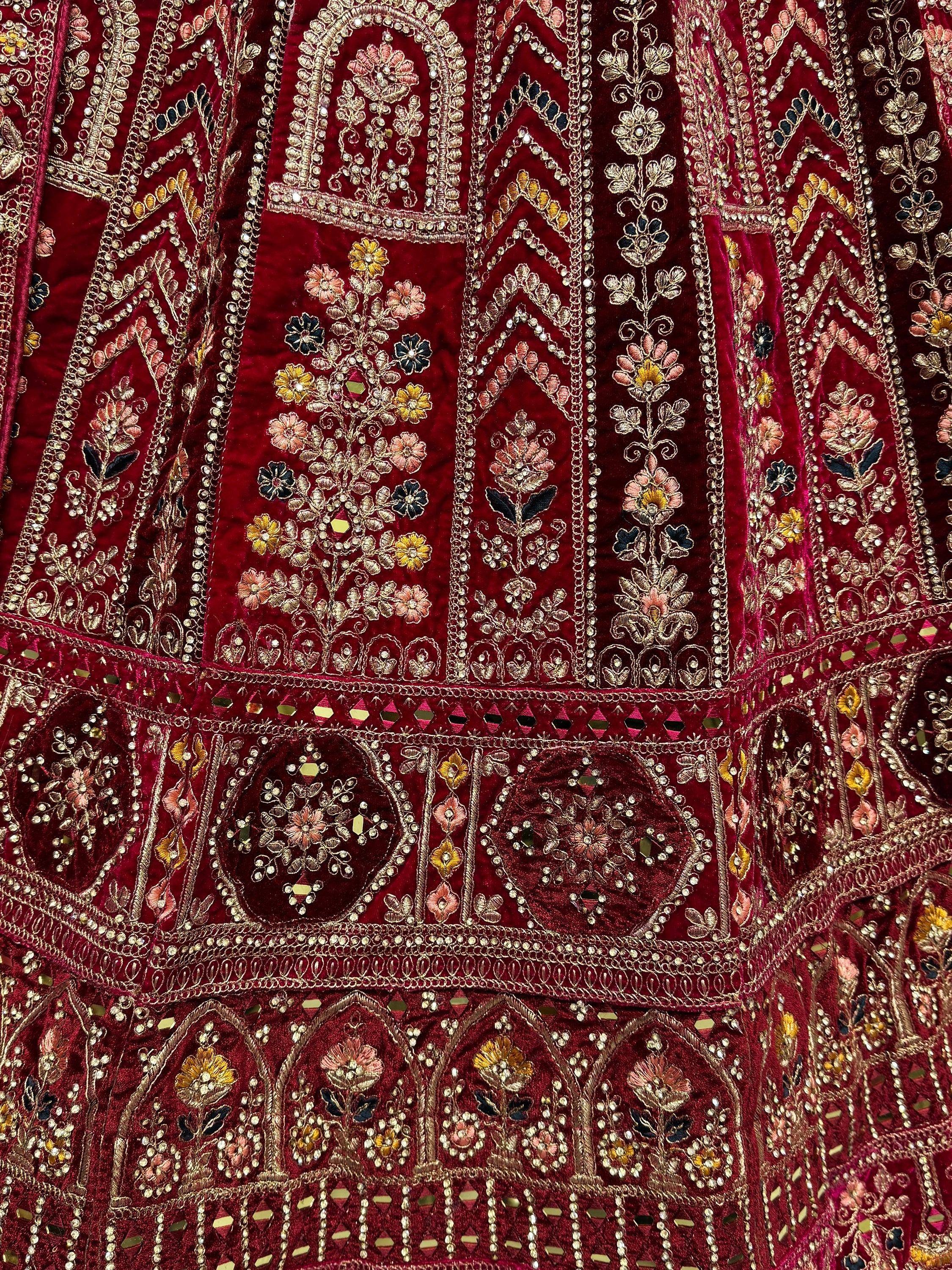 Richly embroidered maroon velvet ethnic wear with floral motifs and mirror work, perfect for festive occasions.