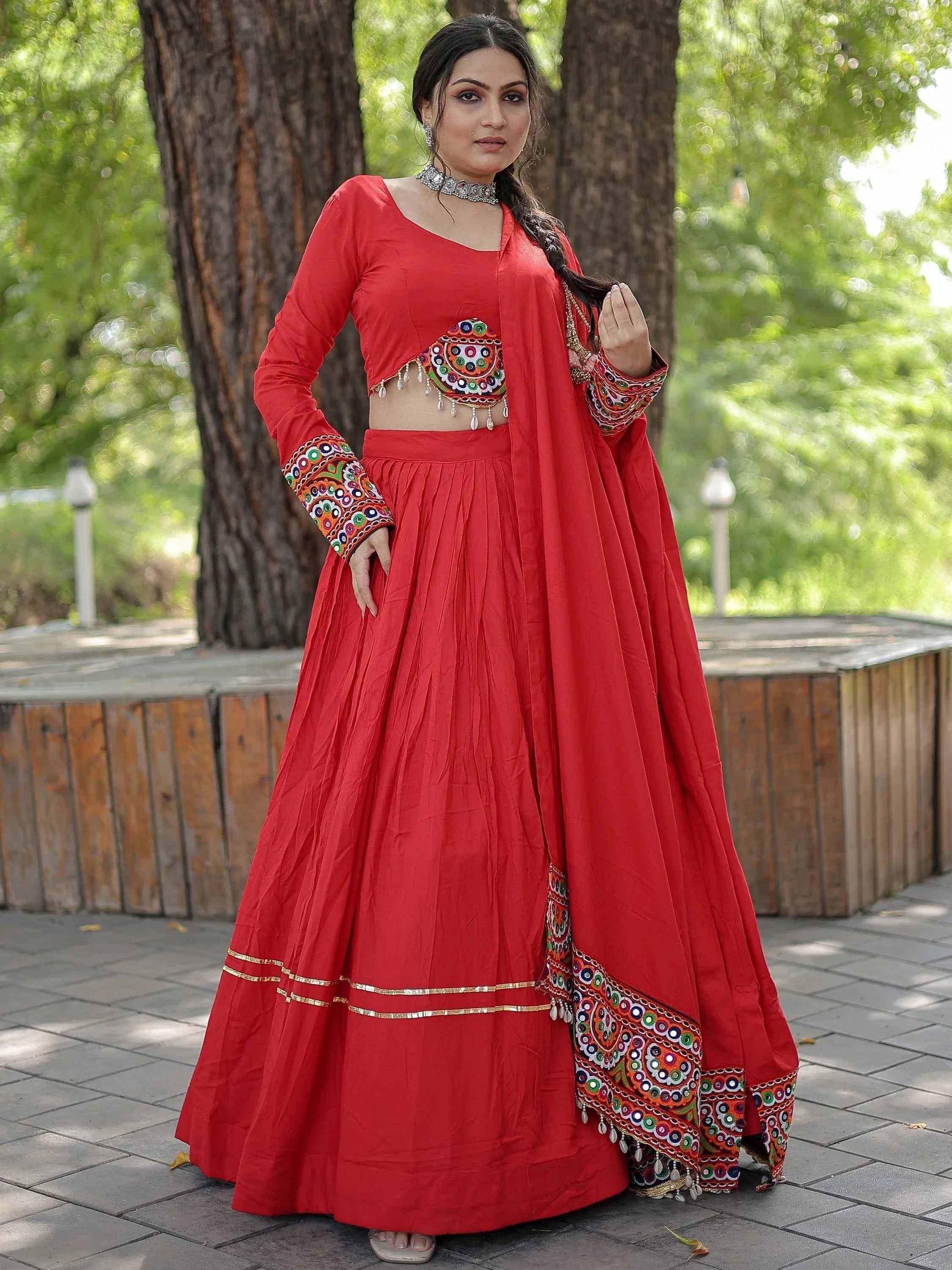 Red ethnic lehenga choli with mirror work and gold trim, perfect for Indian festivals and weddings