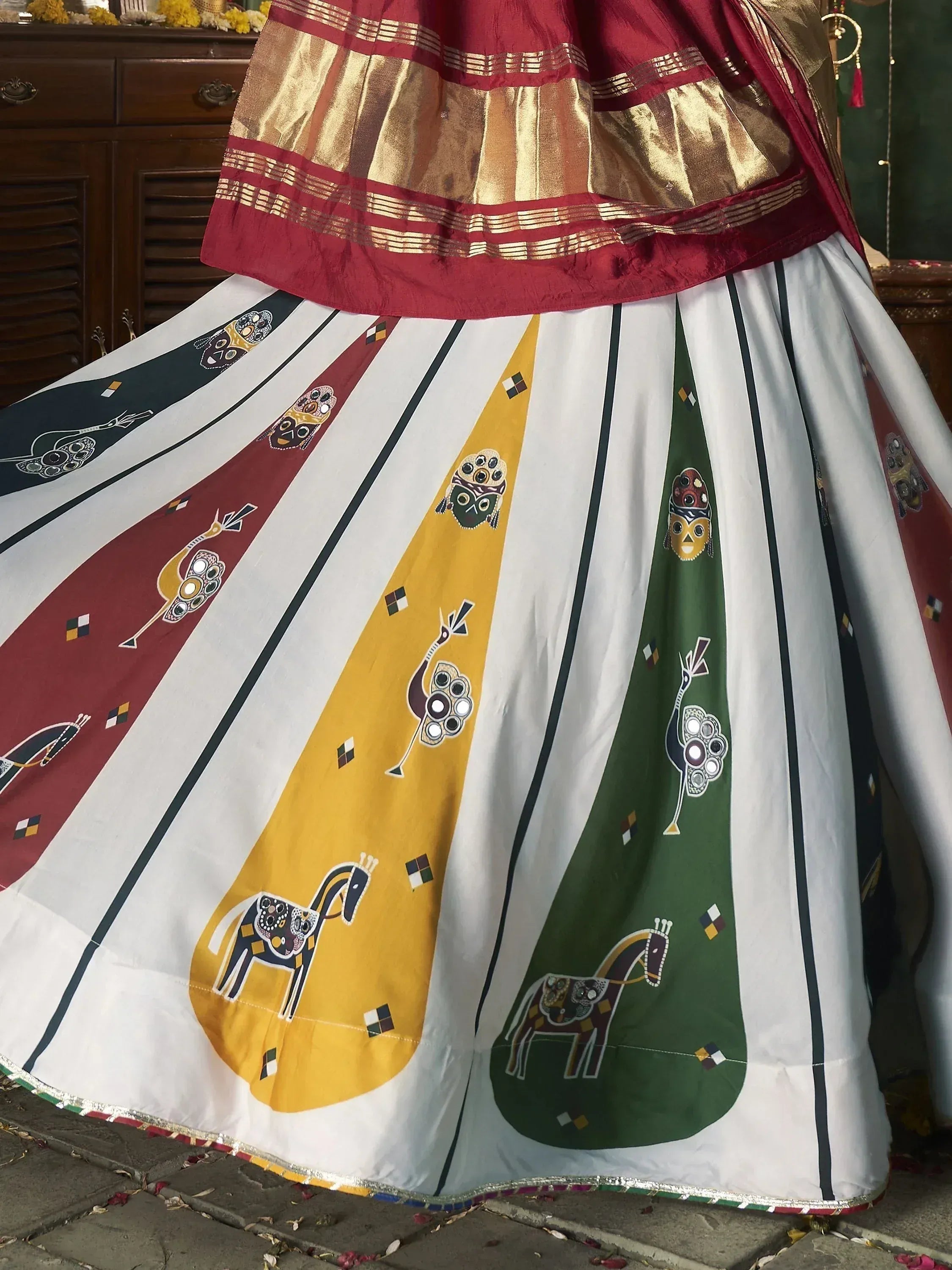 Ethnic lehenga choli with colorful tribal print skirt and gold border, perfect for Indian festive occasions