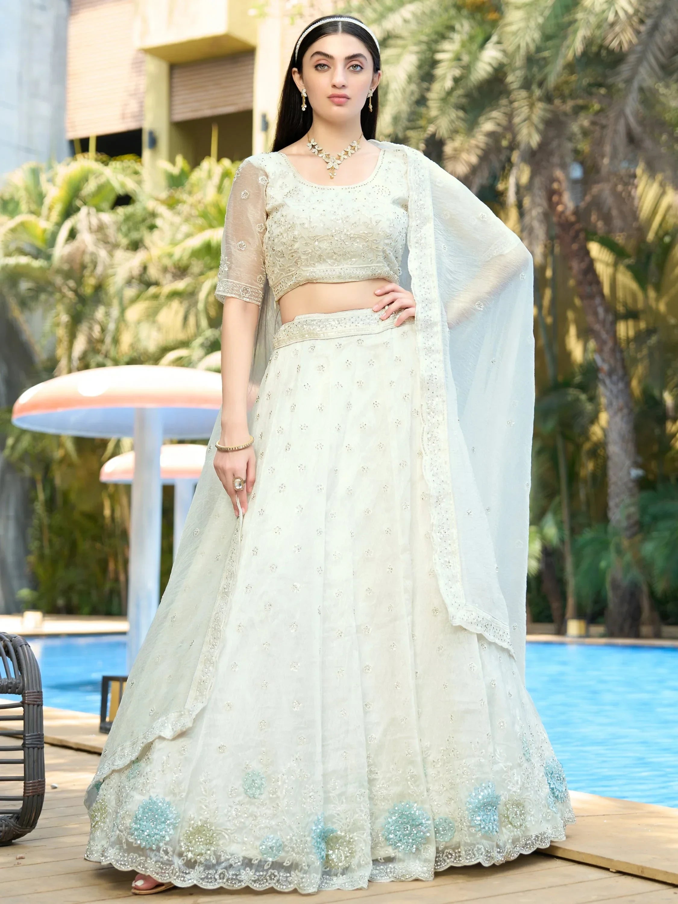 Elegant white embroidered lehenga choli with blue floral details, perfect for Indian weddings and parties.