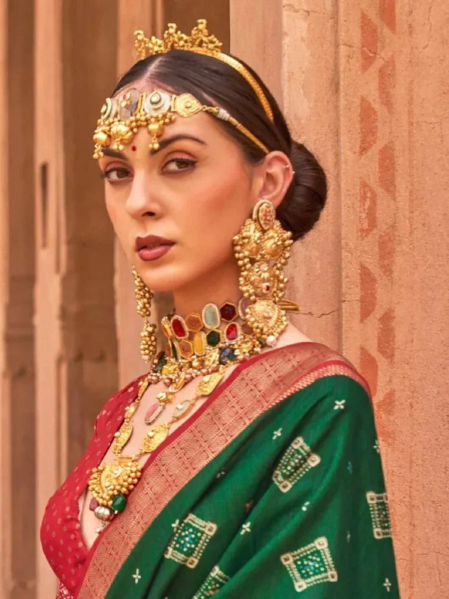 Woman in green and red saree with heavy gold jewelry and traditional Indian headpiece
