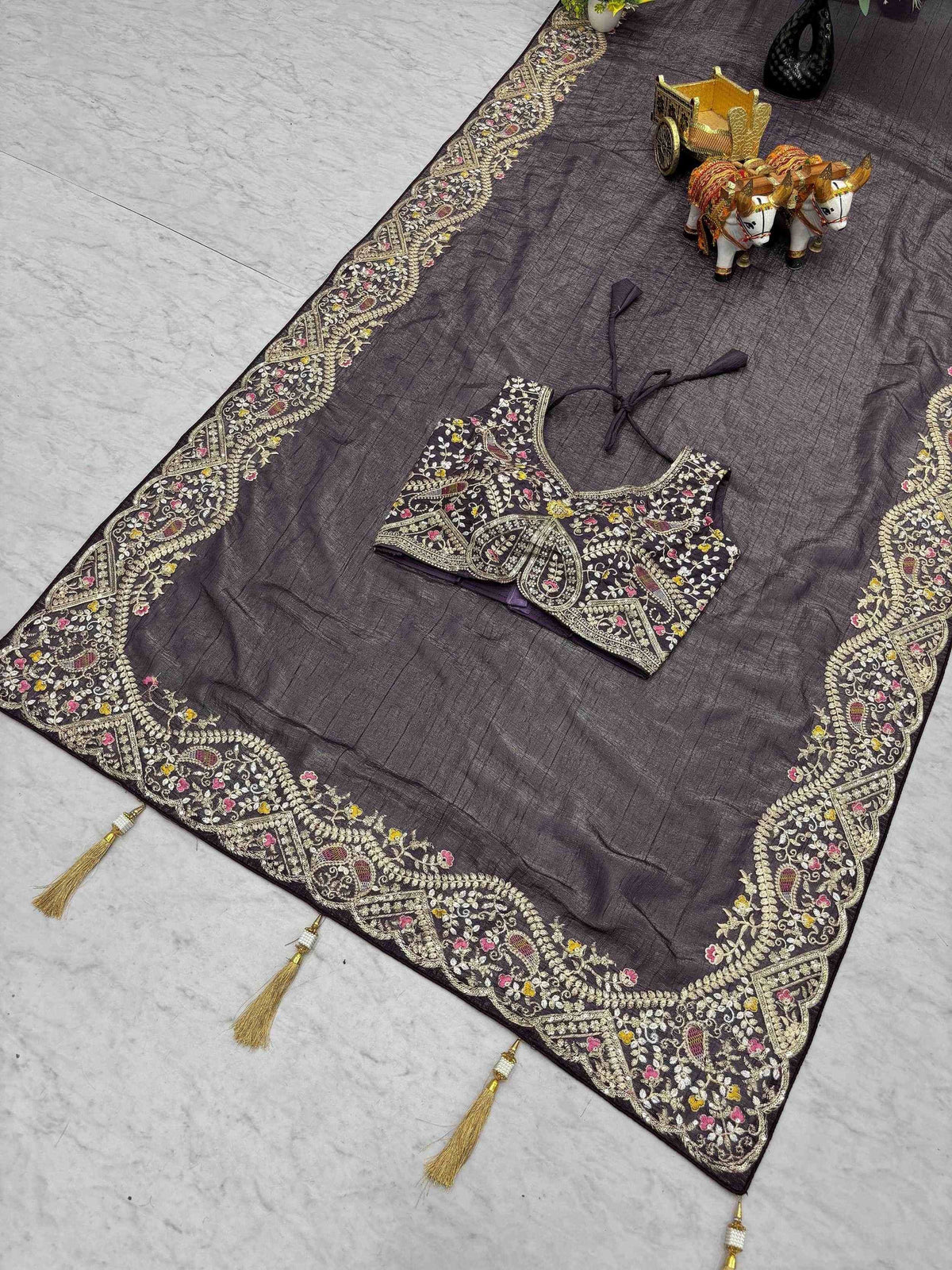 Elegant black embroidered saree with floral motifs and golden tassels, paired with matching blouse.