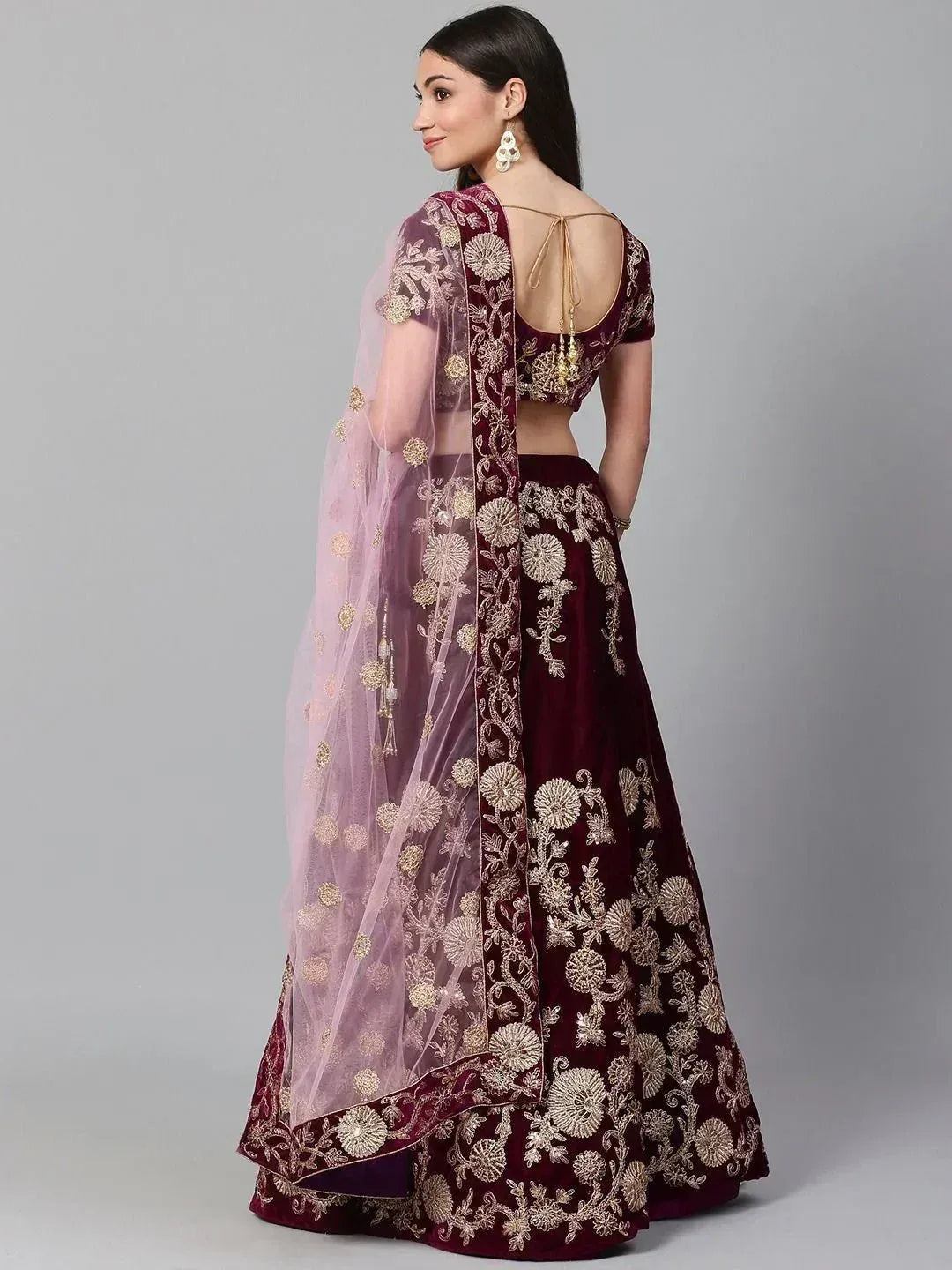 Maroon velvet lehenga choli with gold floral embroidery and sheer pink dupatta, back view