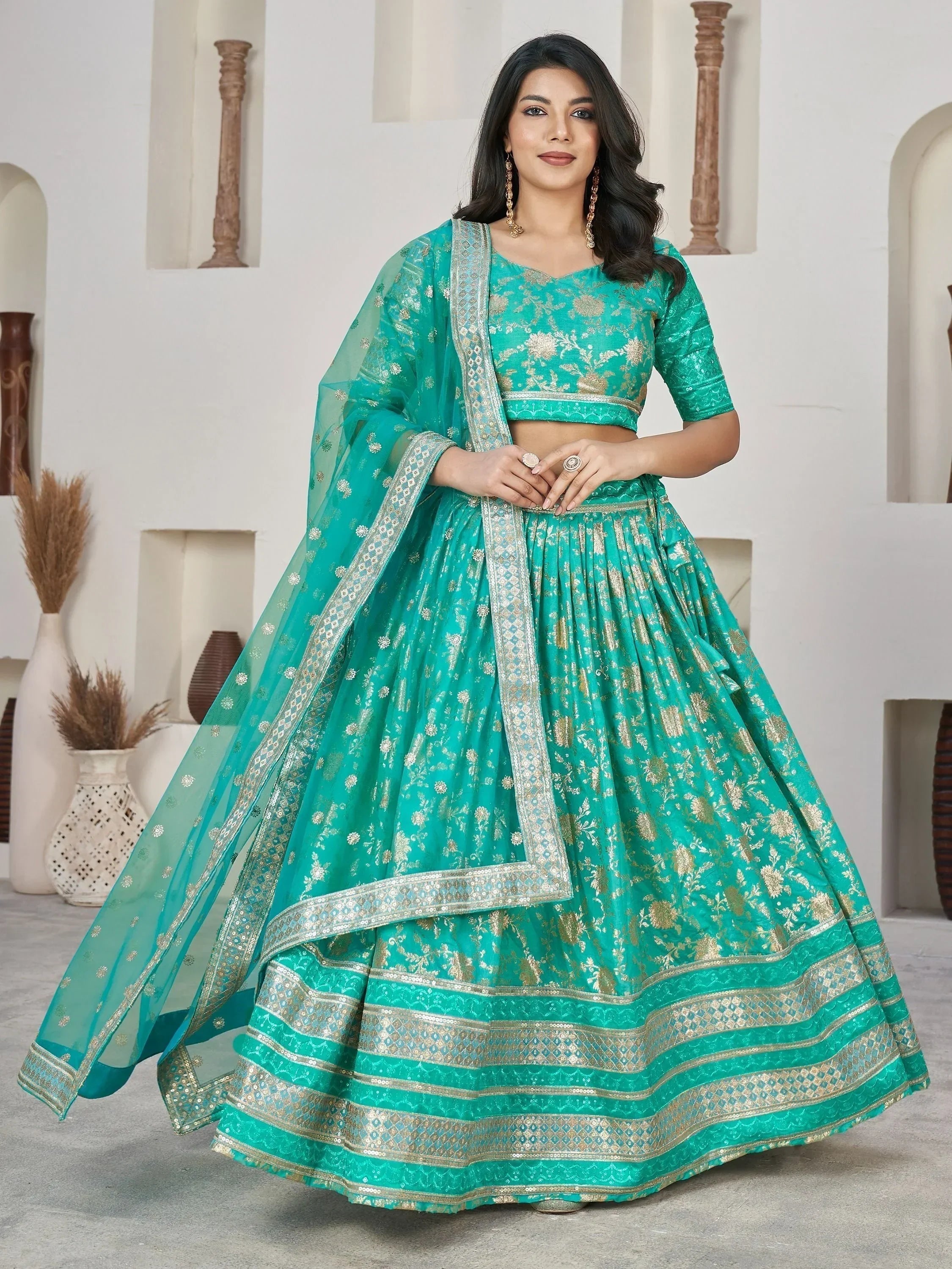 Teal green designer lehenga choli with gold floral embroidery and sequin border, perfect for weddings and festivals.