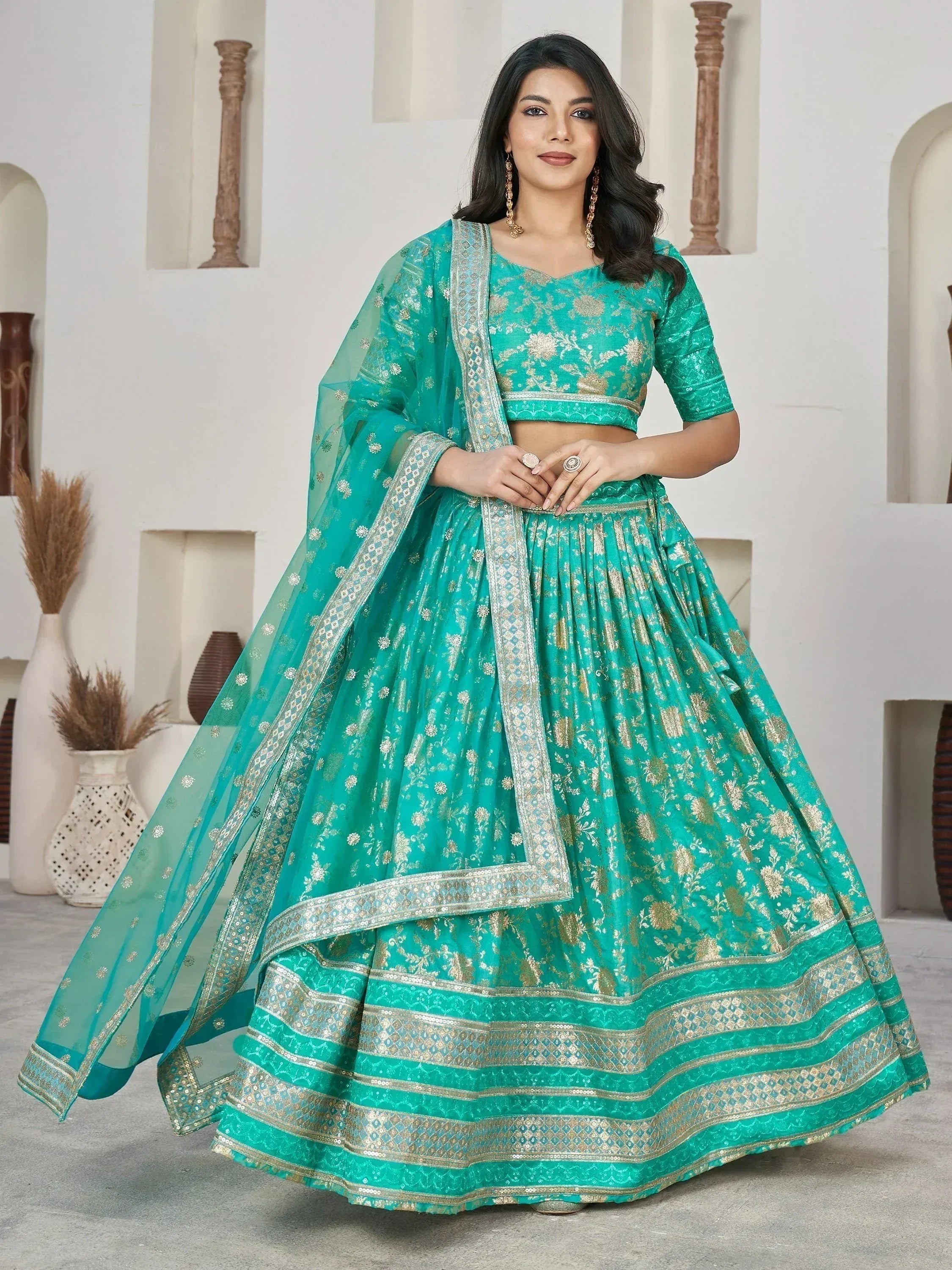 Teal green designer lehenga choli with gold floral embroidery and sequin border, perfect for weddings and festivals.