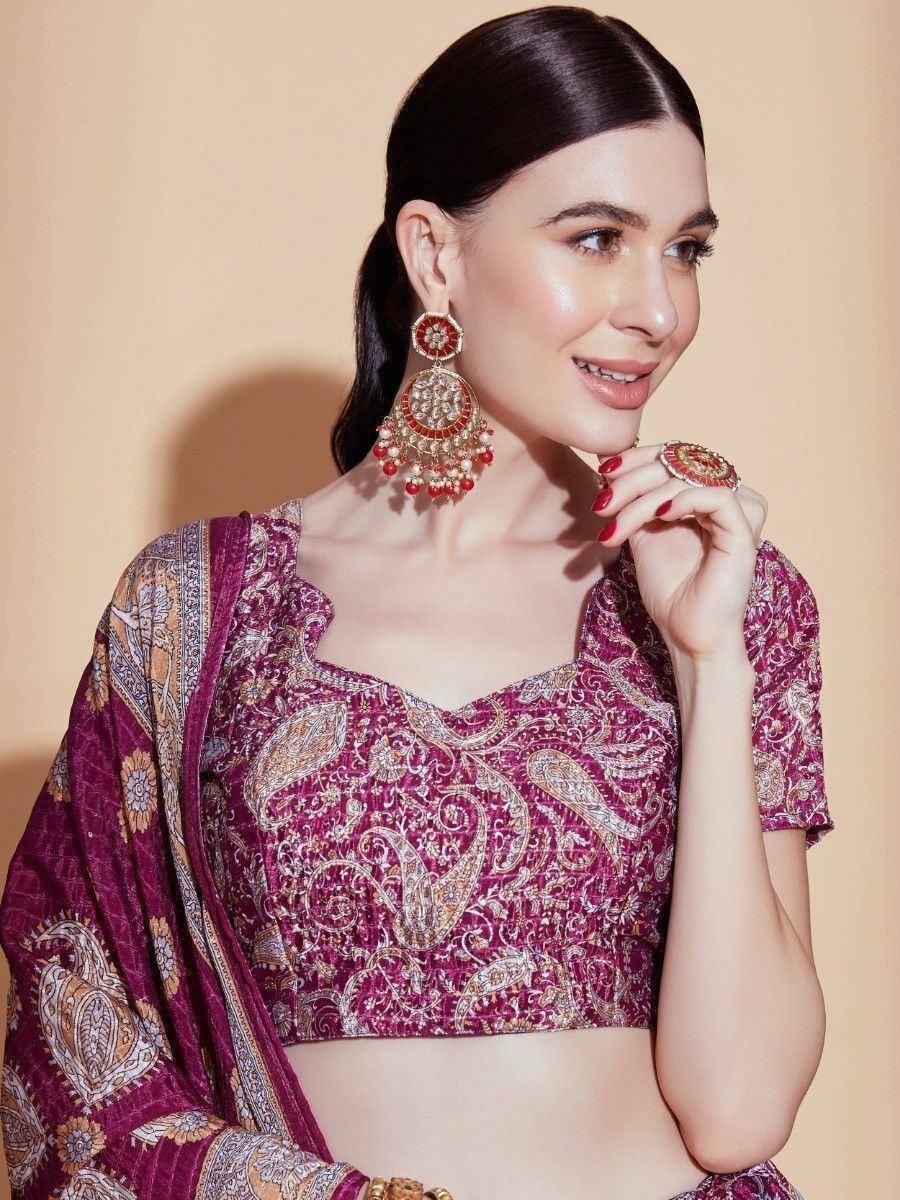 Woman in maroon paisley print lehenga choli with gold embroidery and traditional jhumka earrings