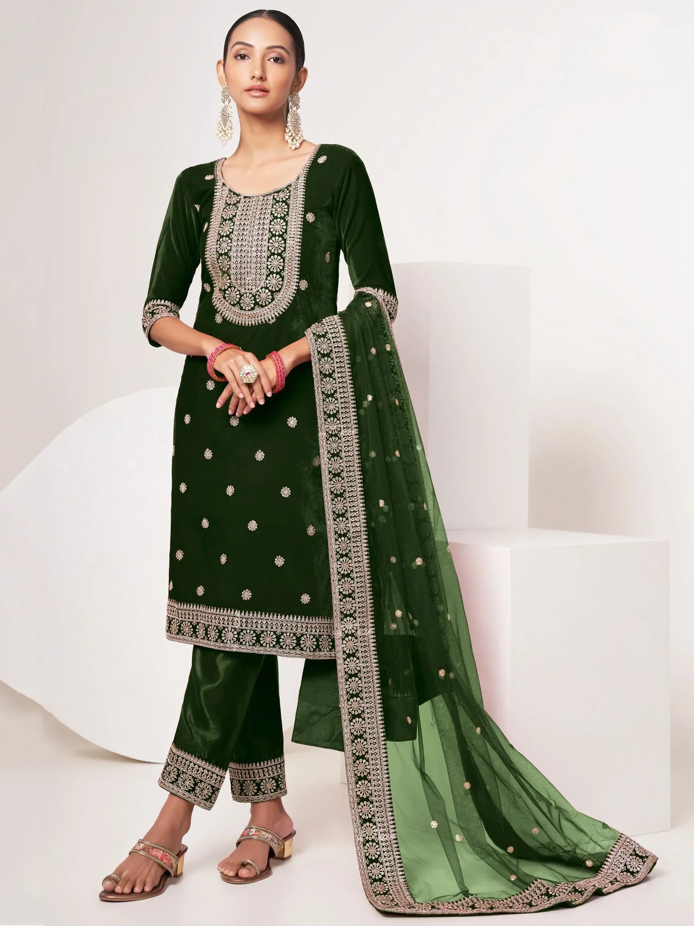 Woman wearing dark green embroidered salwar kameez with matching dupatta, ethnic jewelry