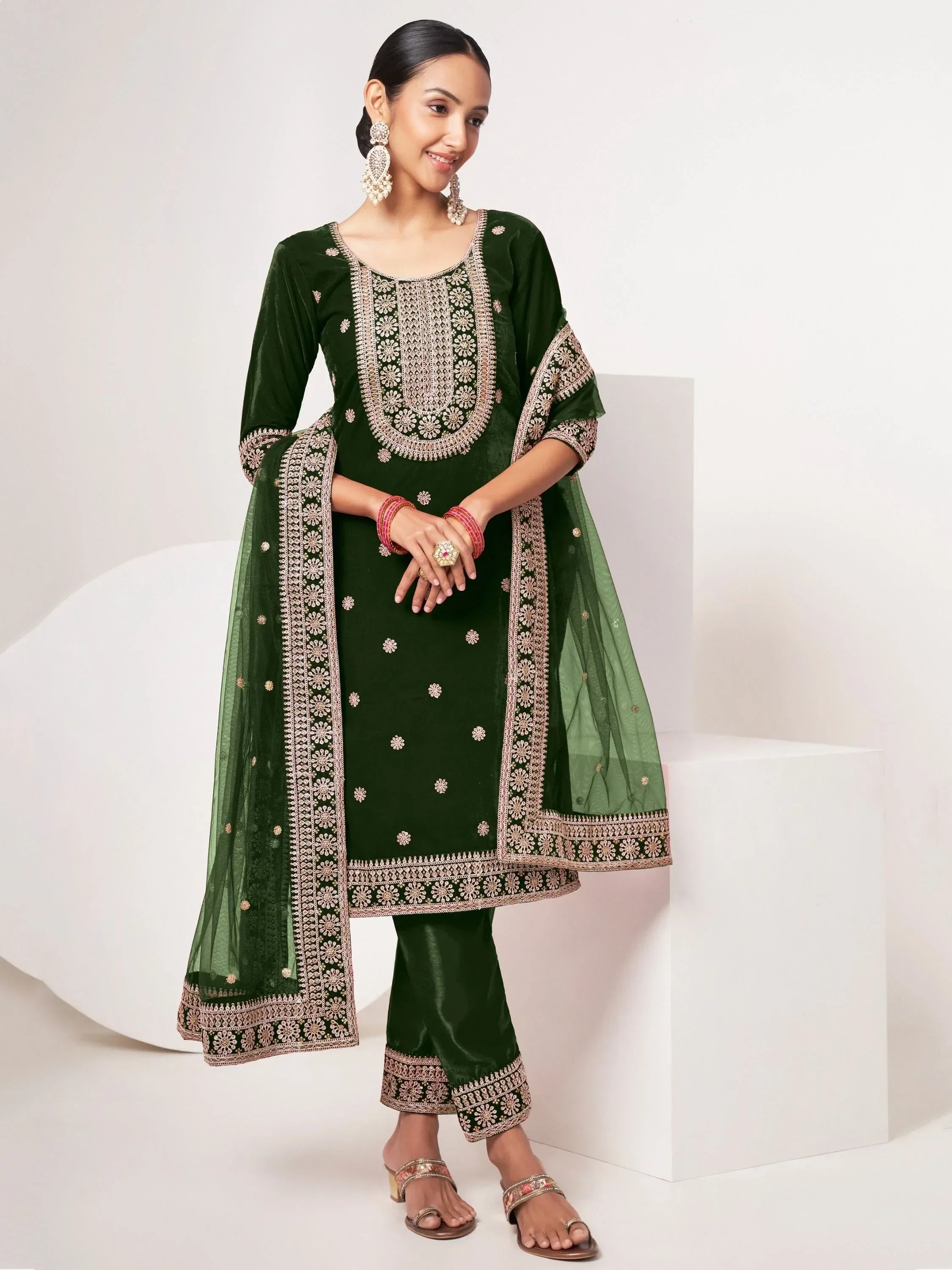Woman wearing dark green embroidered salwar kameez with matching dupatta and traditional jewelry