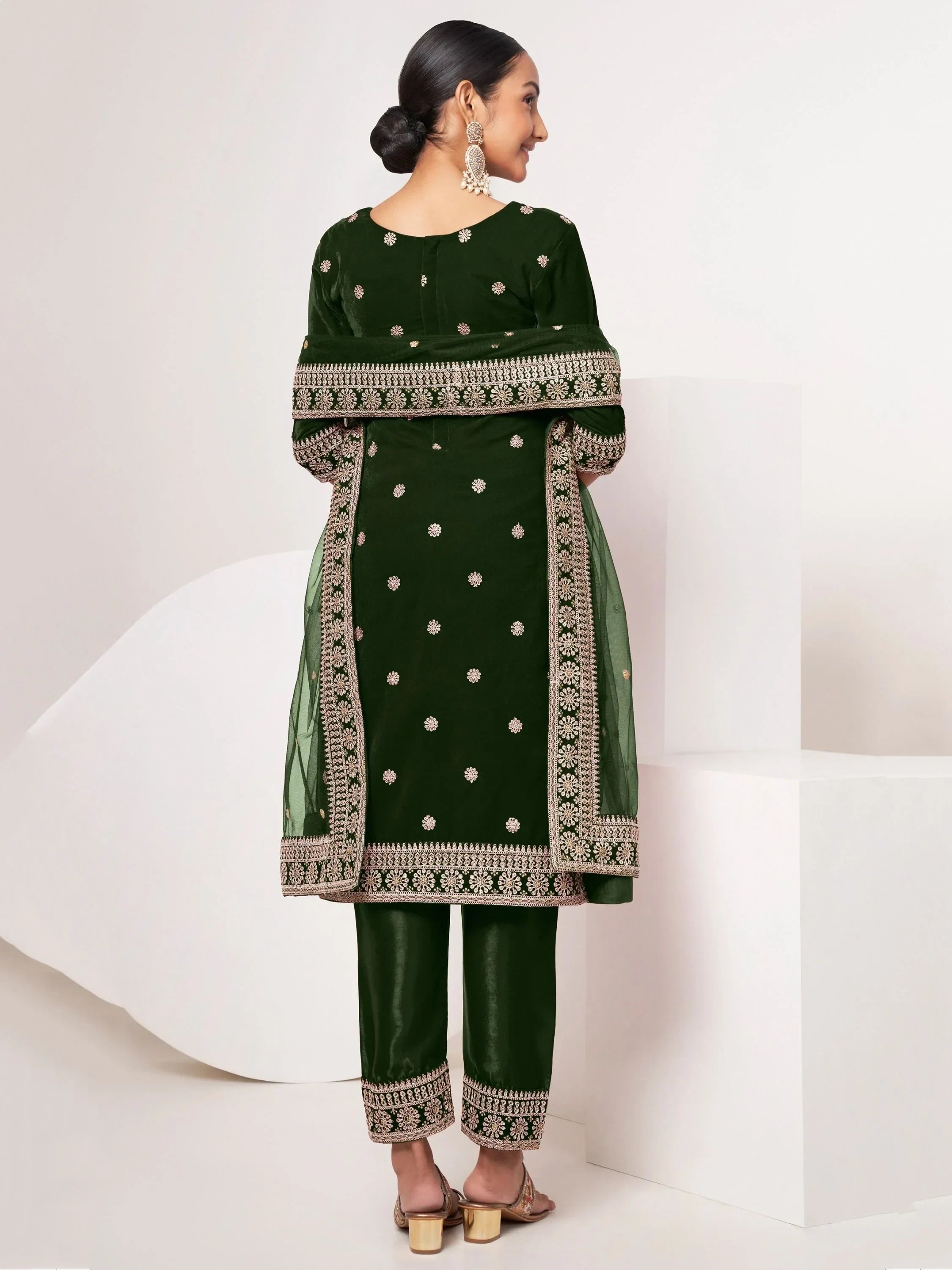 Woman wearing dark green embroidered salwar kameez with dupatta and gold heels