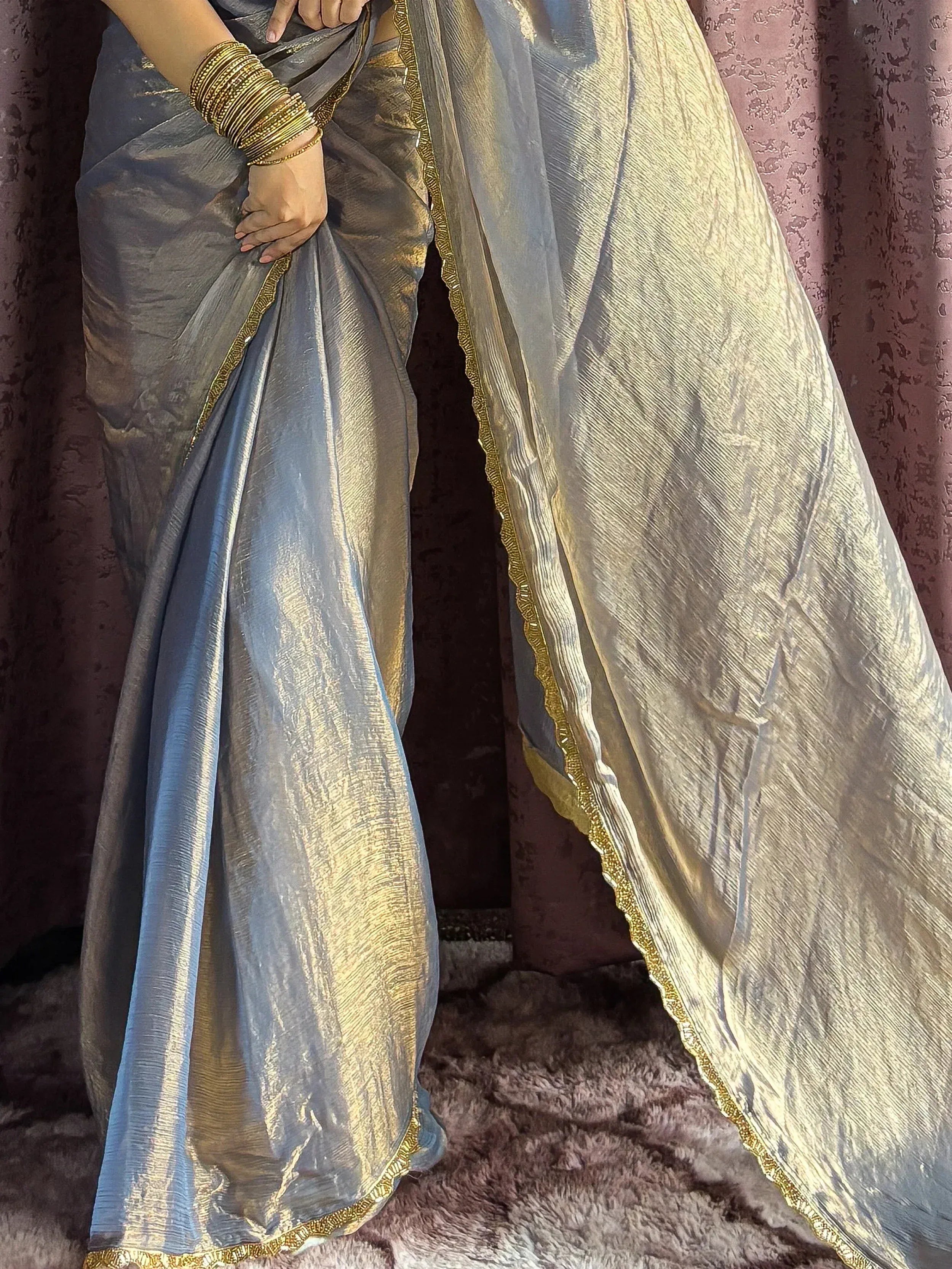 Elegant grey and gold saree with intricate border, styled with traditional bangles for Indian ethnic wear.