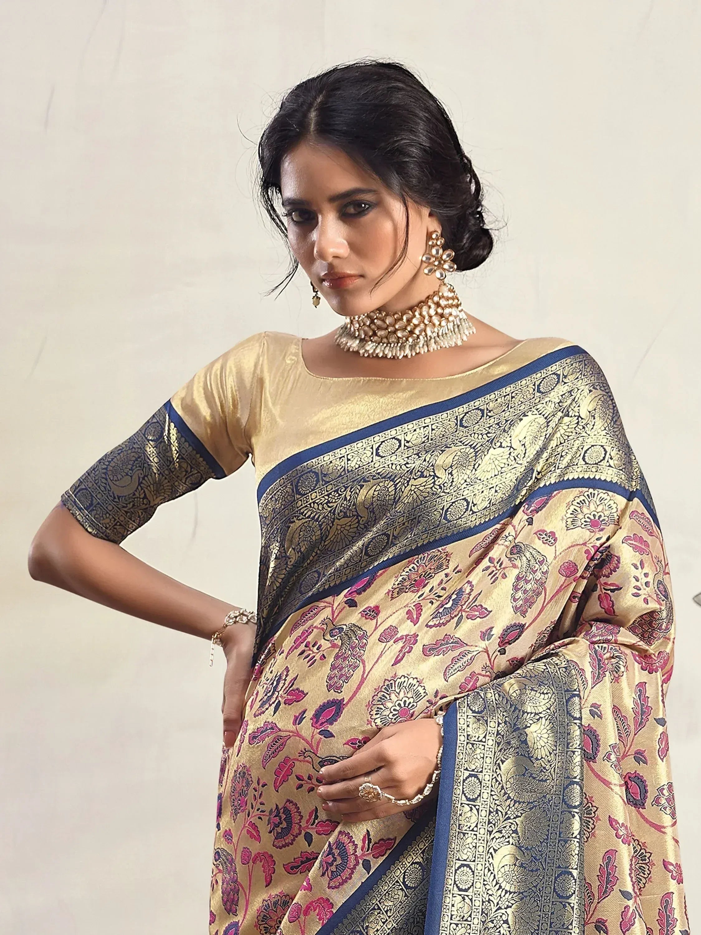 Elegant gold and blue floral saree with intricate border, paired with matching blouse and traditional jewelry