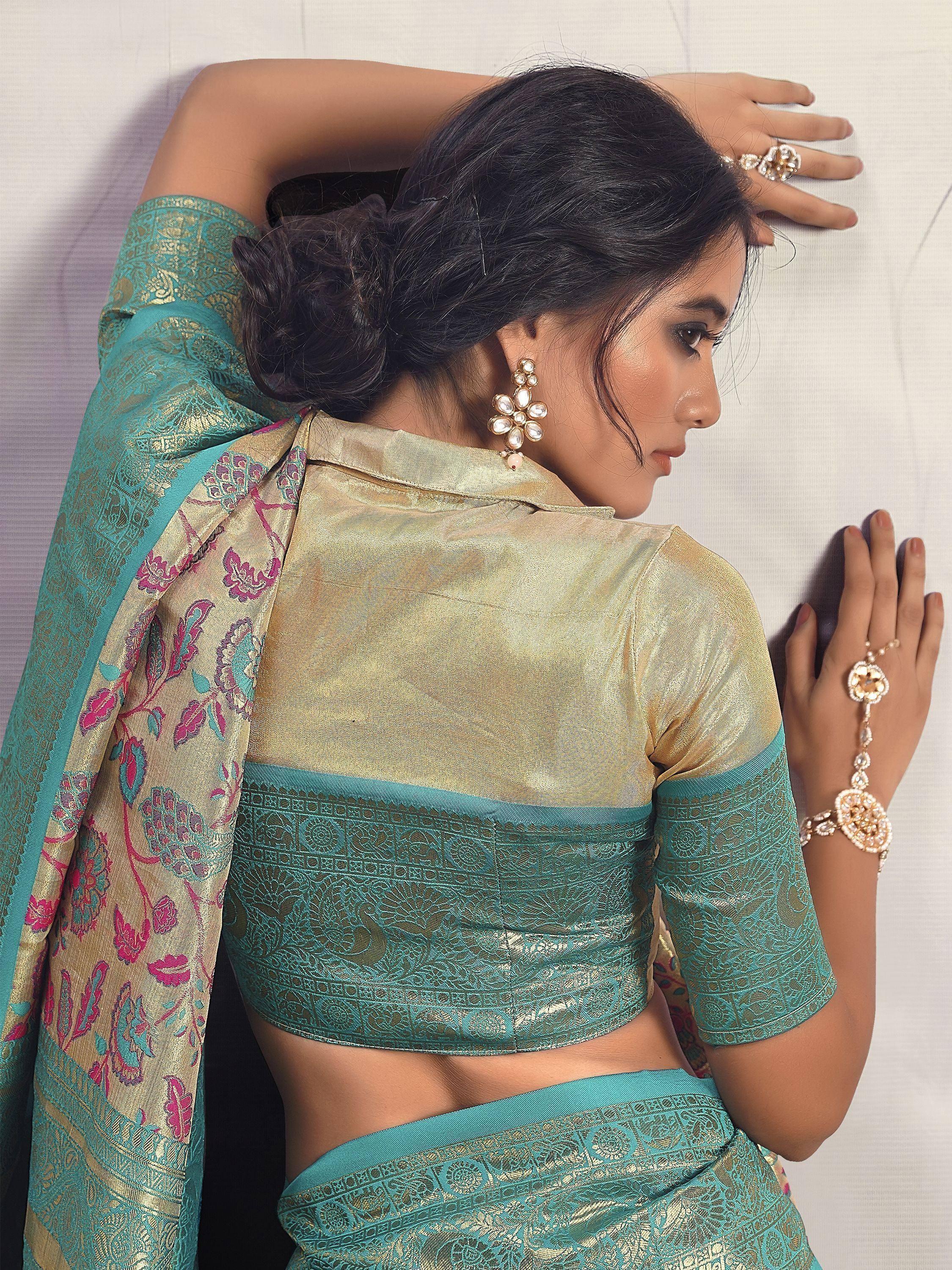 Teal and gold designer saree with floral border, paired with matching blouse and traditional jewelry