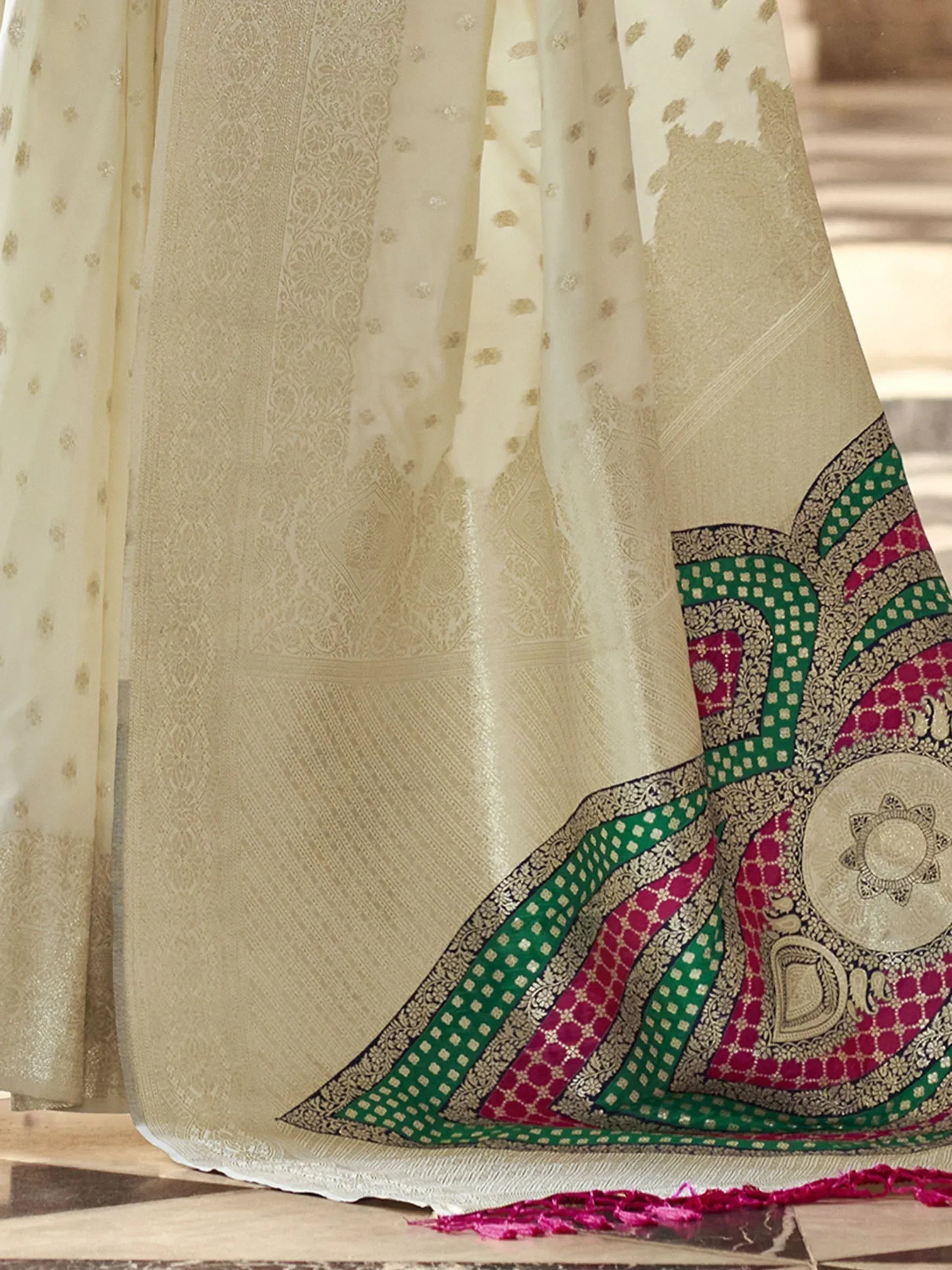 Cream ethnic saree with green and pink border, intricate gold embroidery, perfect for Indian occasions.