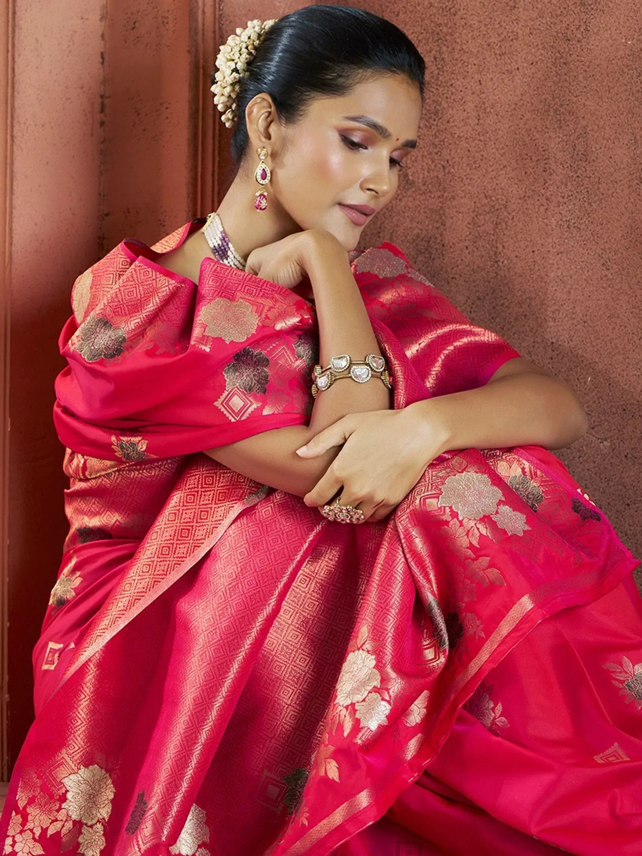 Woman in vibrant pink floral saree with gold embroidery, traditional Indian ethnic wear