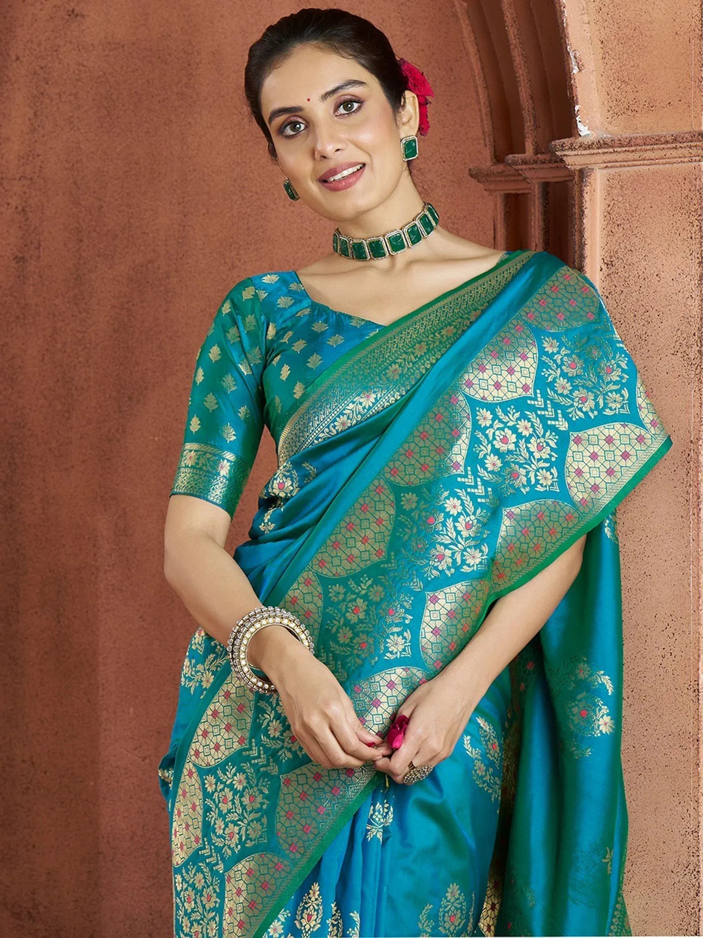 Teal designer saree with gold floral motifs and green border, paired with matching blouse and jewelry