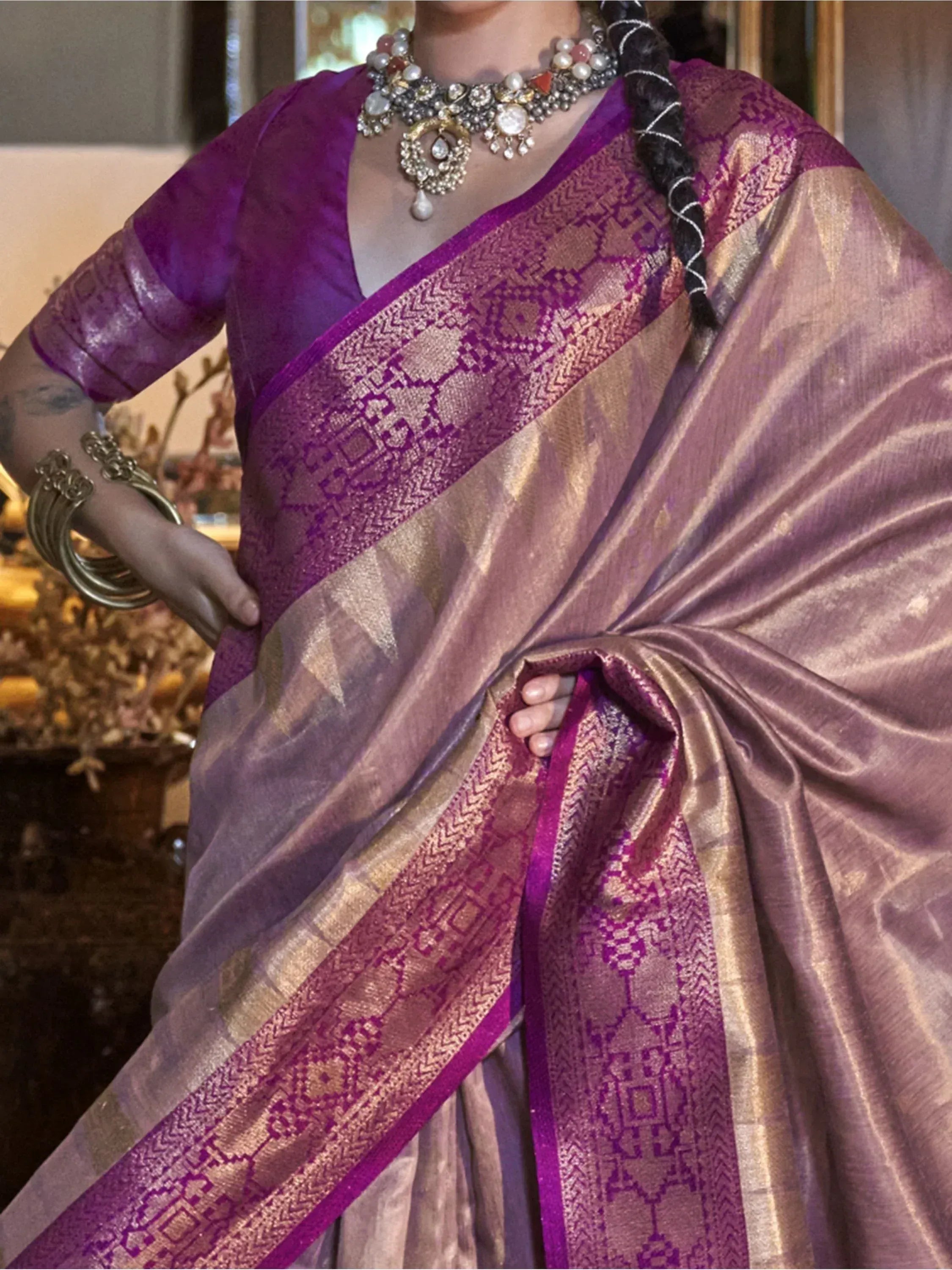 Purple and gold ethnic saree with intricate border, paired with designer jewelry and blouse