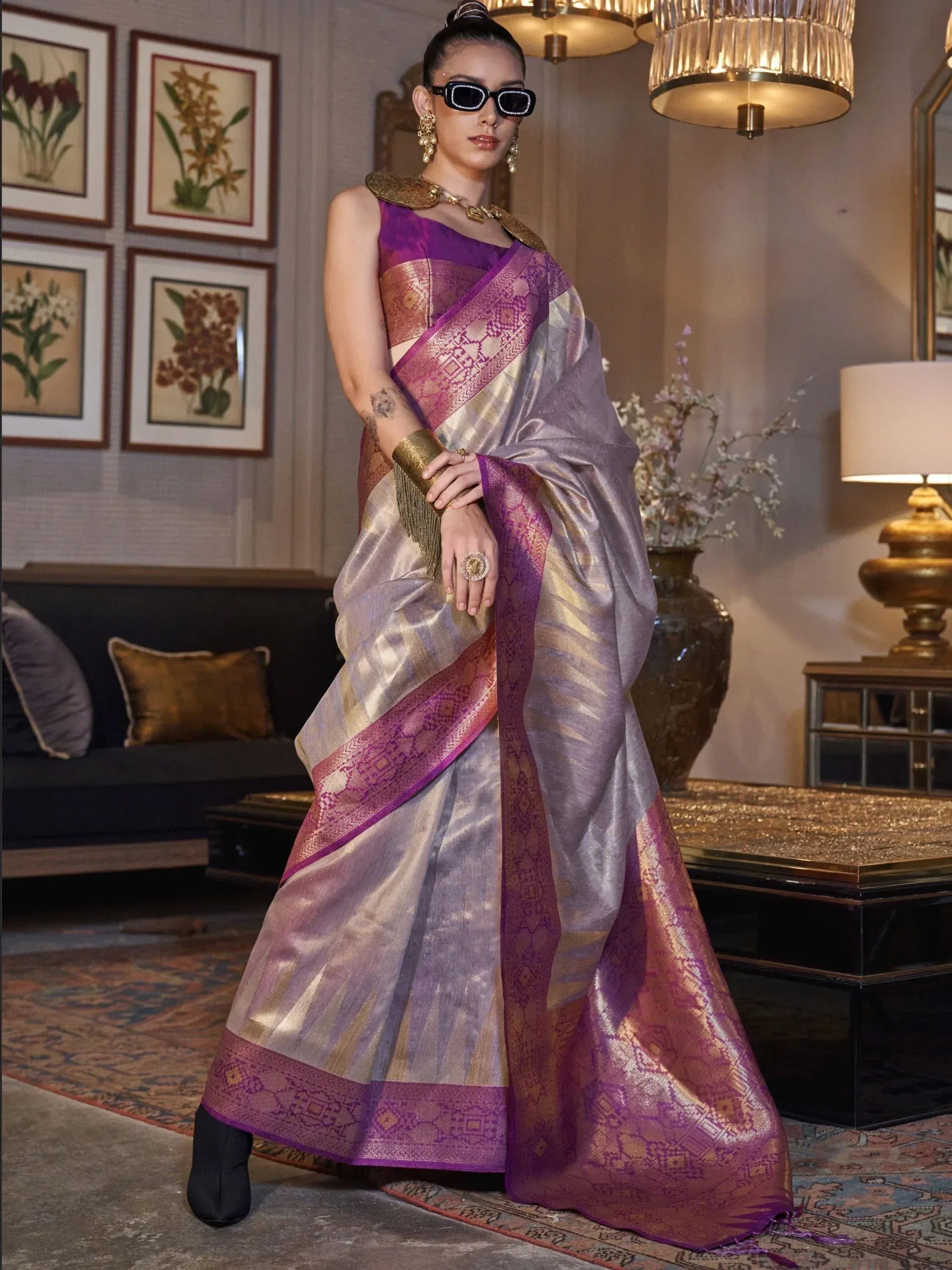 Purple and gold designer saree with intricate border, styled with statement jewelry and sunglasses